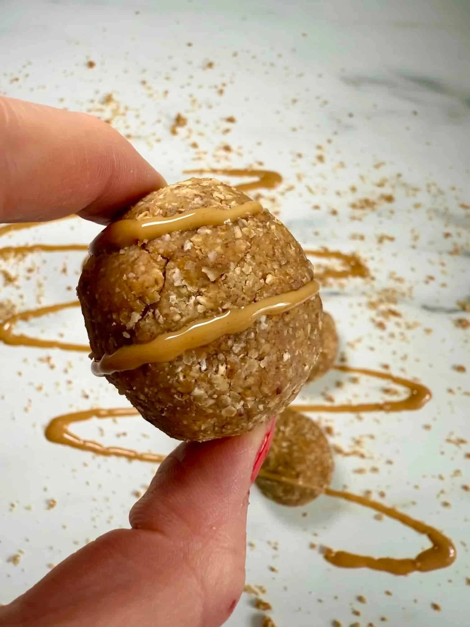 Several oat, date and peanut butter balls topped with peanut butter on serving board