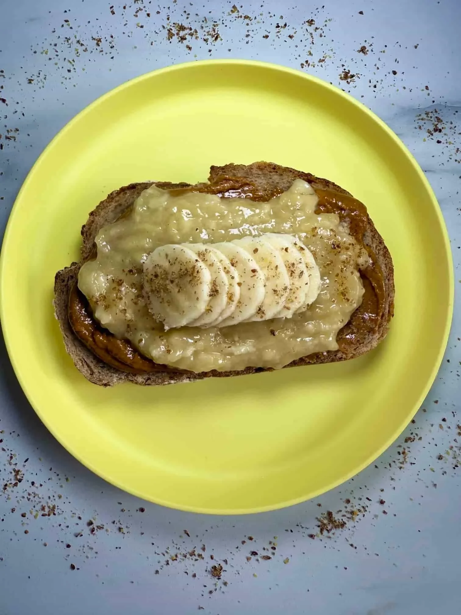 A slice of toast layered with peanut butter, pureed and sliced banana and sprinkled with flaxseed