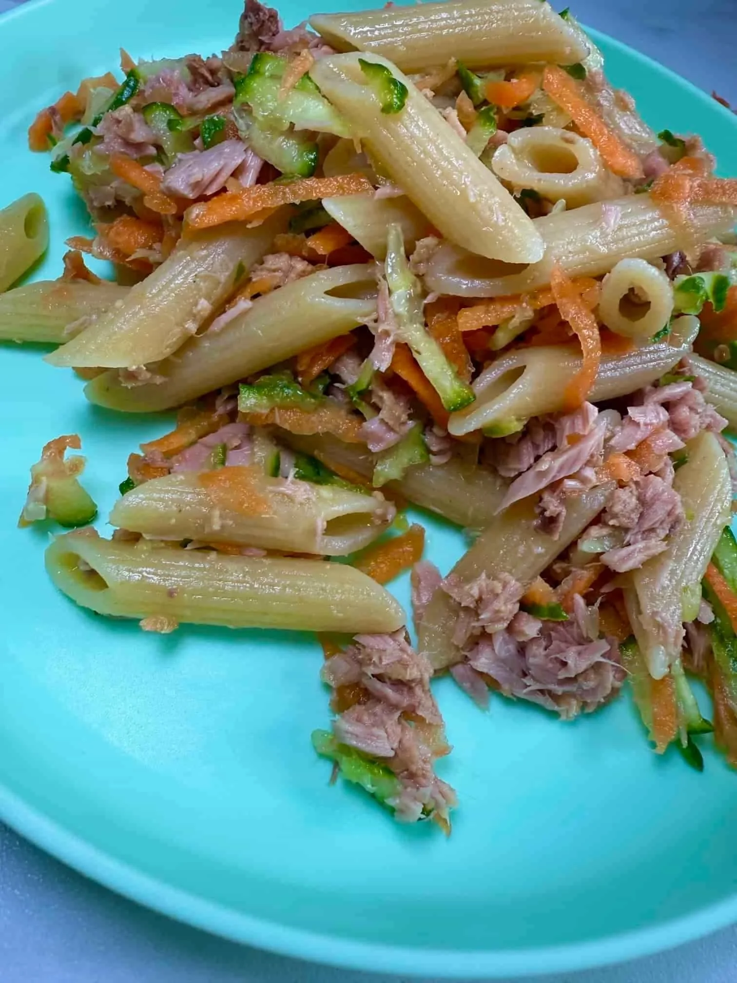 A toddler sized portion of tuna pasta salad with carrot and cucumber