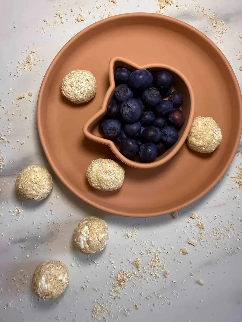 Cottage cheese and oat balls served with blueberries on a toddler plate