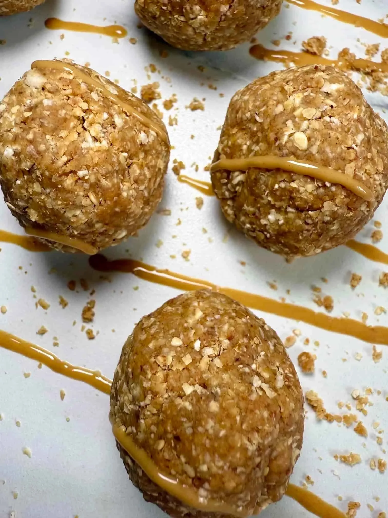 Several oat, date and peanut butter balls topped with peanut butter on serving board