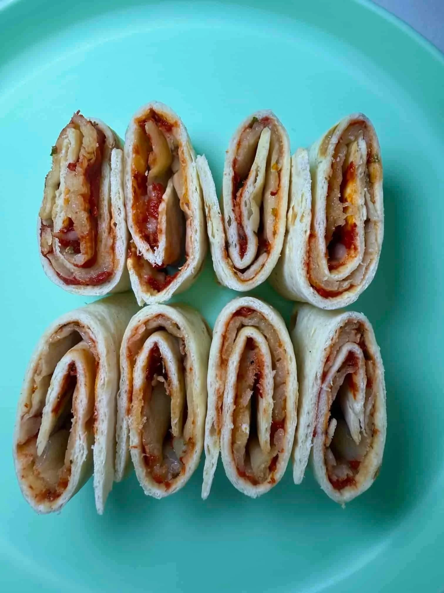 Several tortilla pizza roll-ups, sliced and standing on serving dish