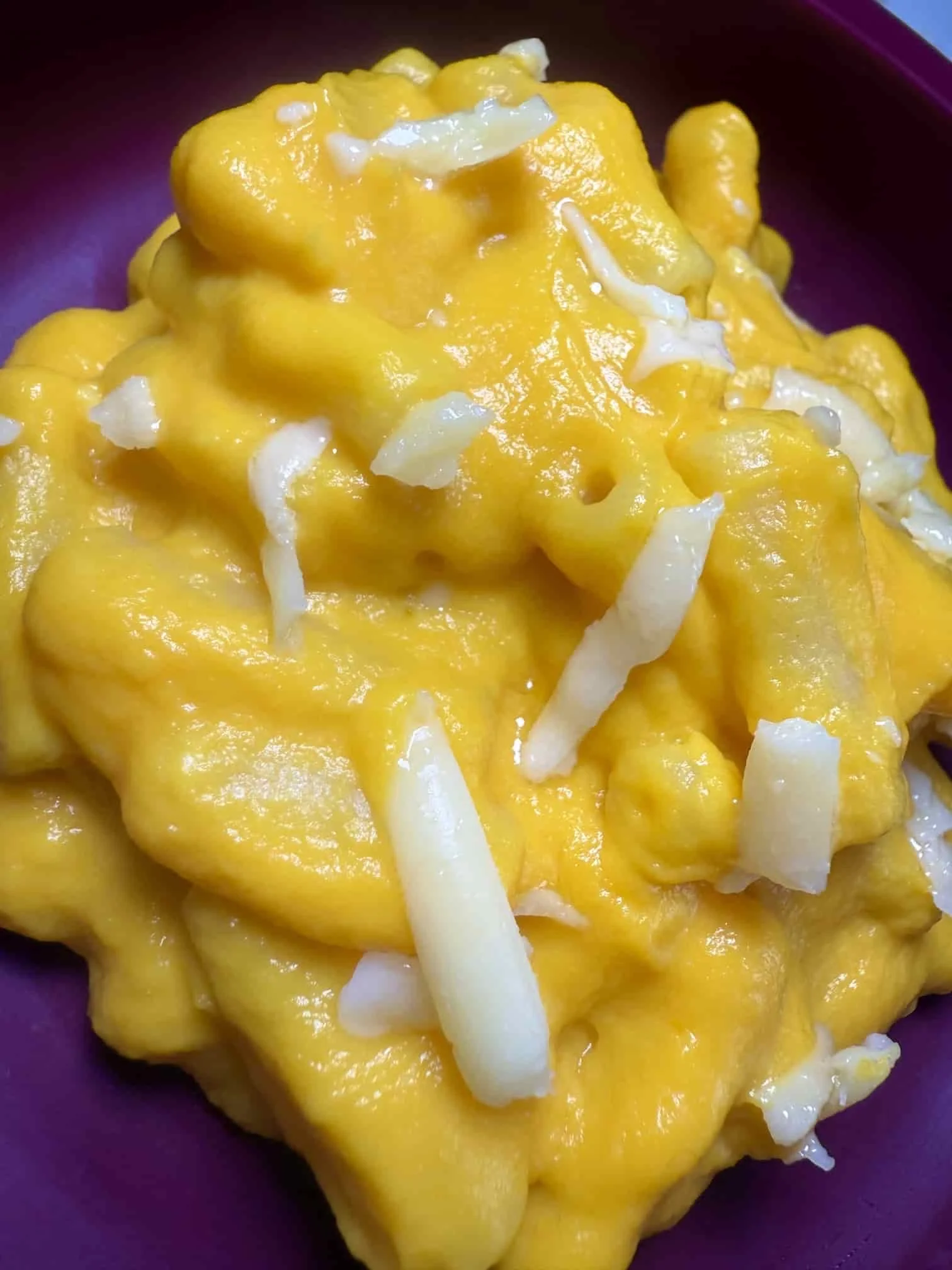 A serving of mac and cheese topped with grated cheese on toddler plate
