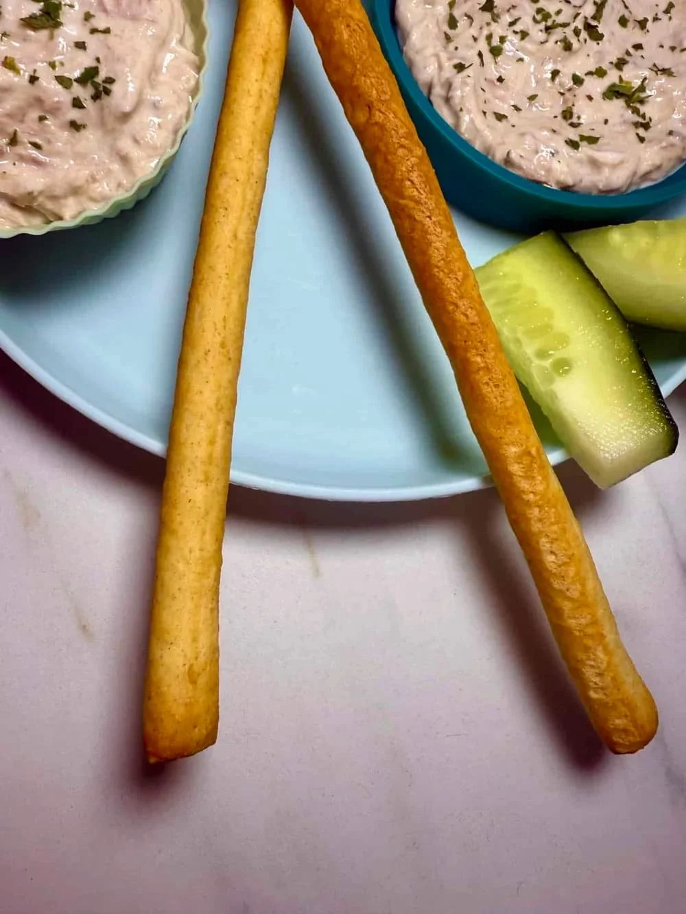 Cream cheese and tuna dip served in silicone case with breadsticks and sticks of cucumber