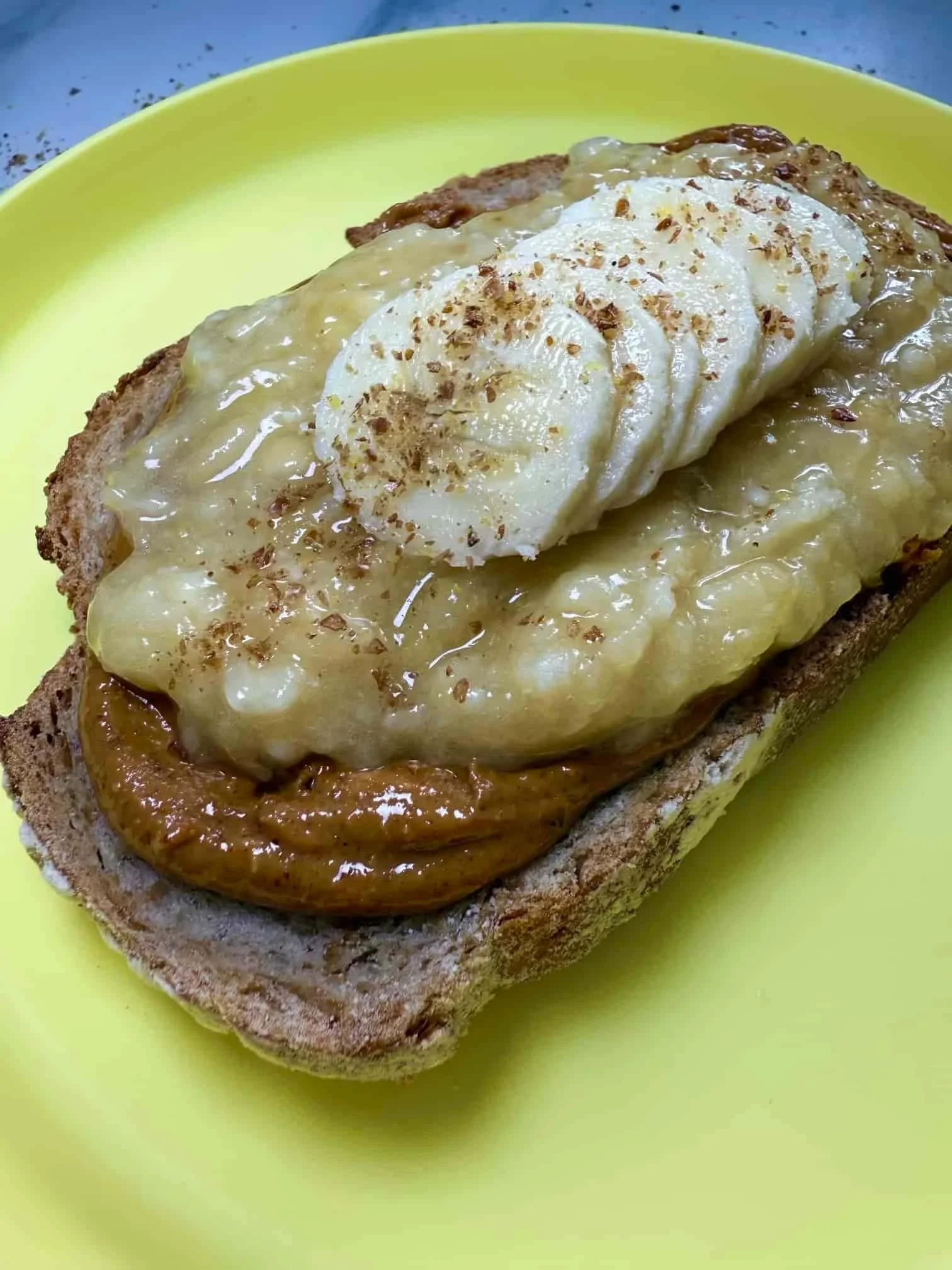 A slice of toast layered with peanut butter, pureed and sliced banana and sprinkled with flaxseed