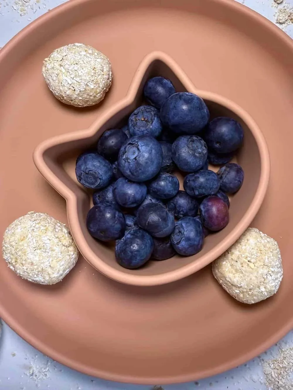 Cottage cheese and oat balls served with blueberries on a toddler plate