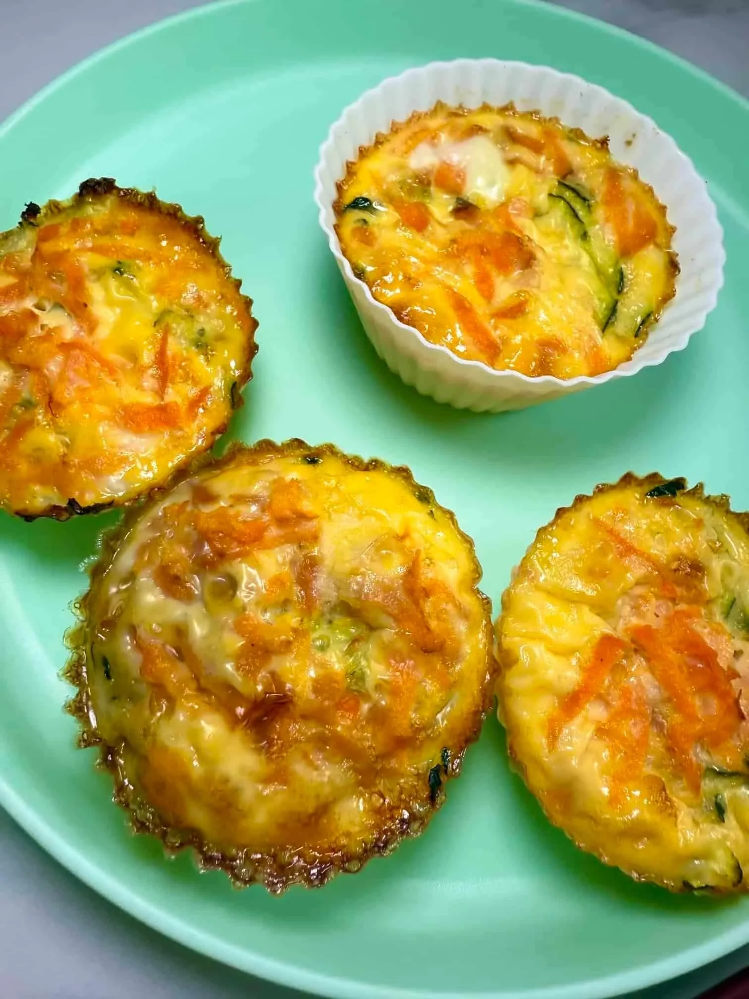 Four baked egg muffins in silicone cases on toddler plate