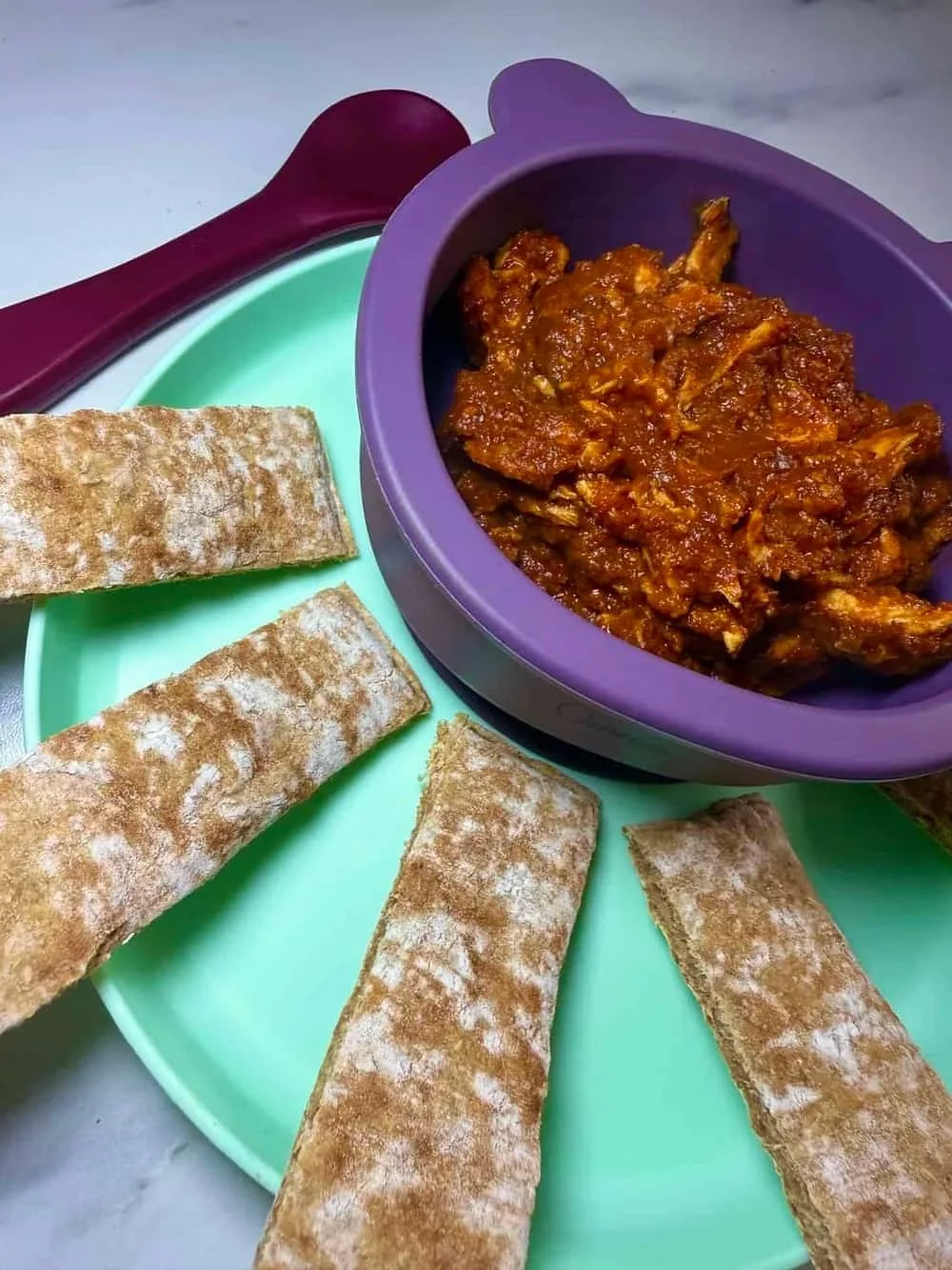 A toddler size bowl of chicken curry with leftover chicken served with homemade naan bread