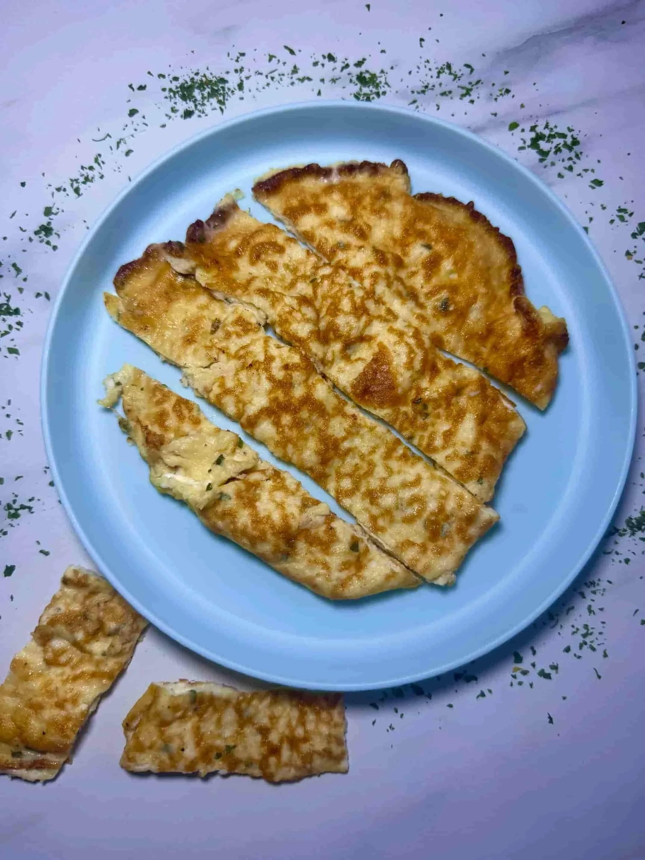 A cooked cottage cheese omlette served on toddler plate and cut into manageable slices