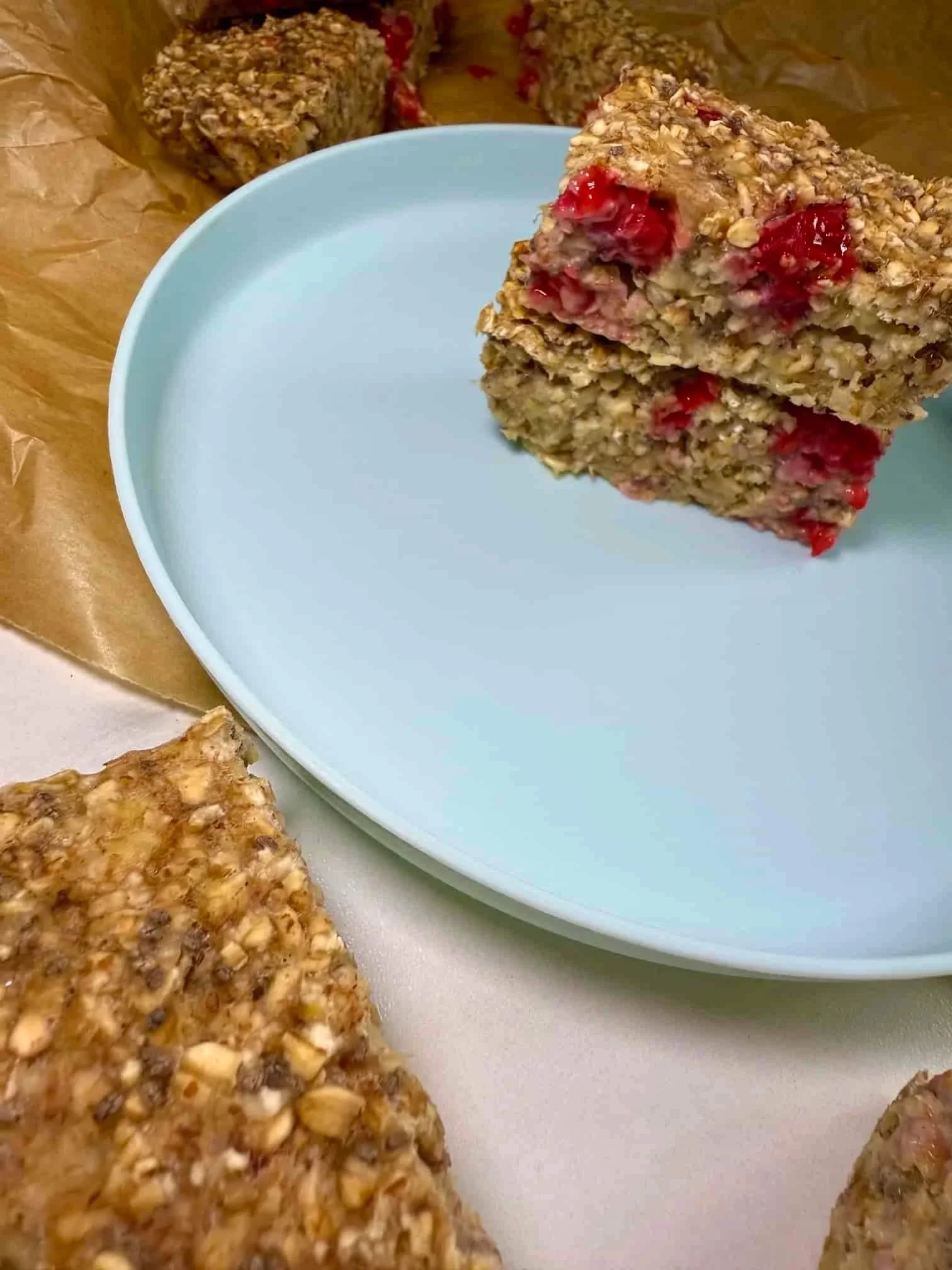Several baked porridge fingers, some stacked on a plate and some resting on parchment paper