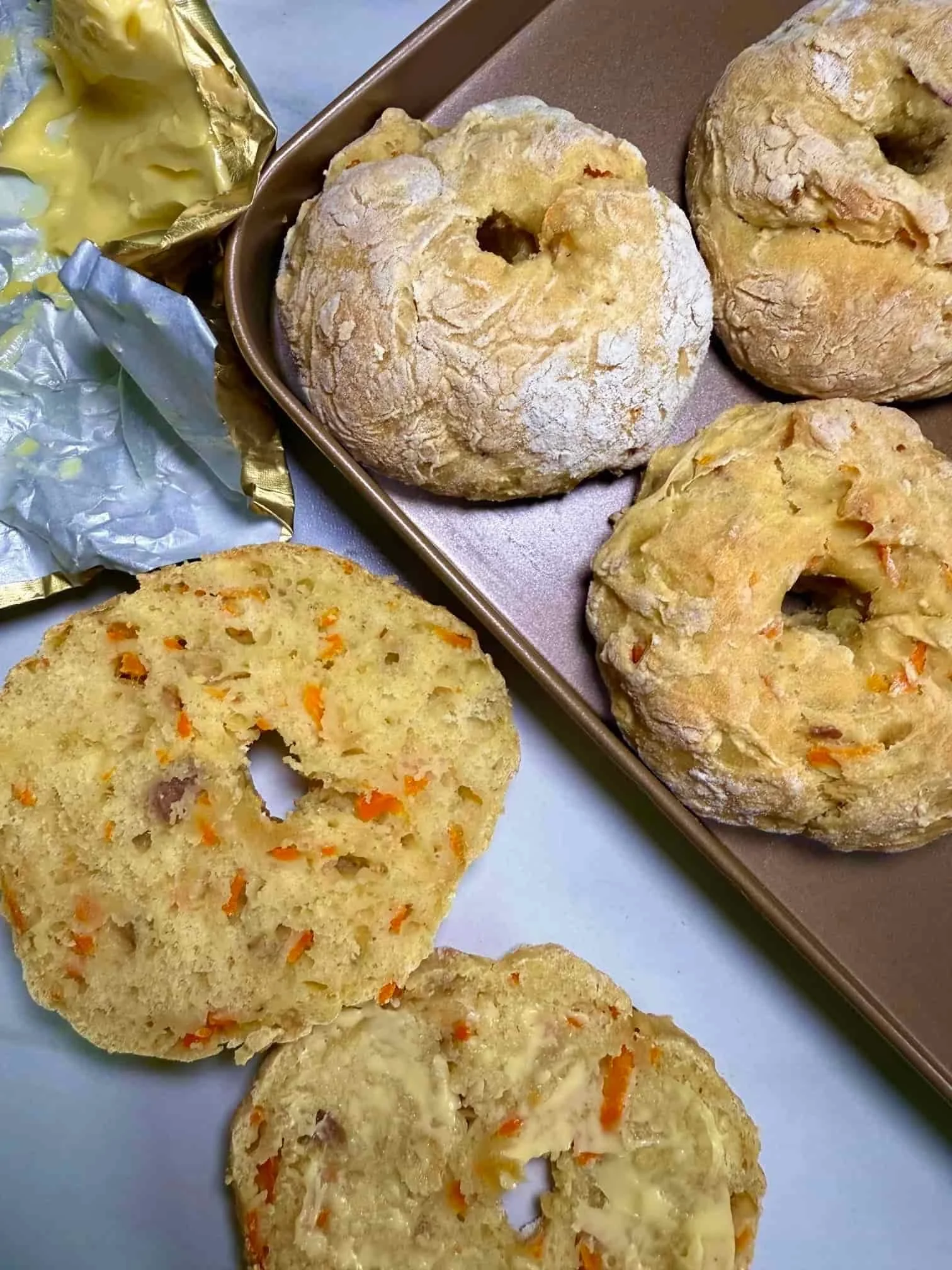 Several baked ABC bagels on baking tray and one cut in half