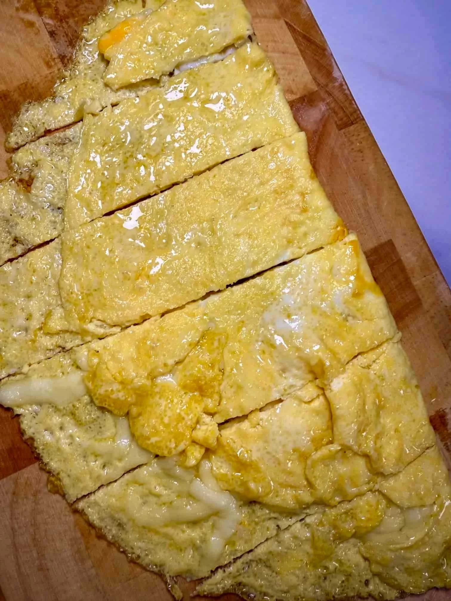 Cooked omelette with cheese, cut into slices and served on wooden board