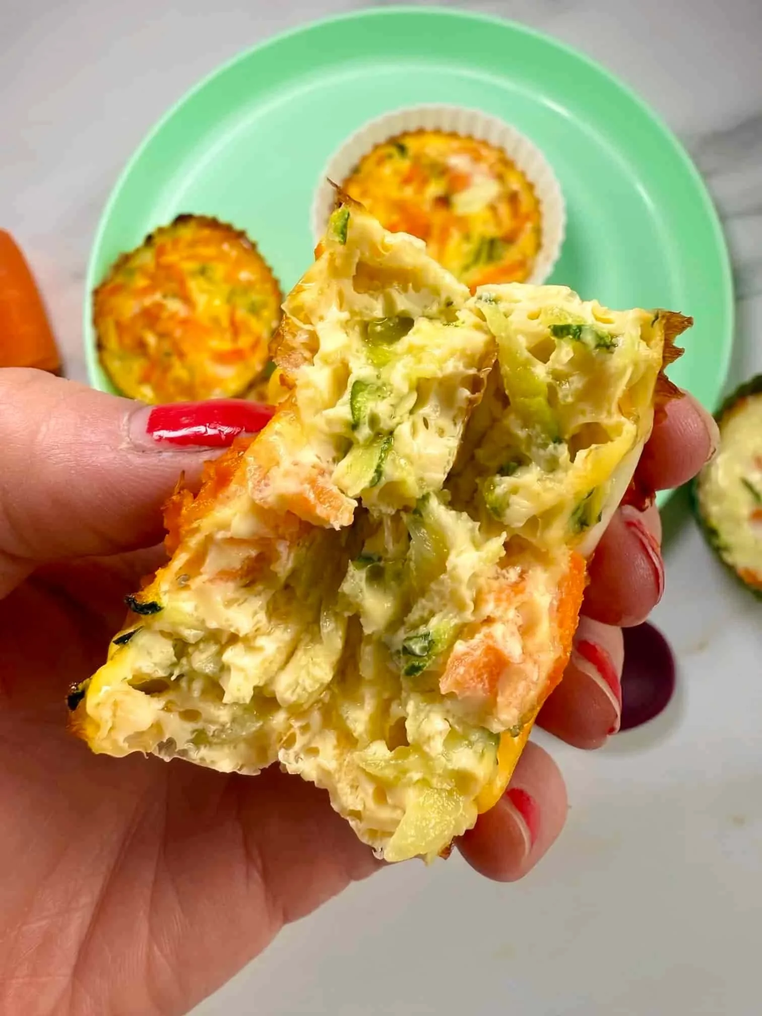 Close up image of a baked egg muffin showing the loaded veggie interior