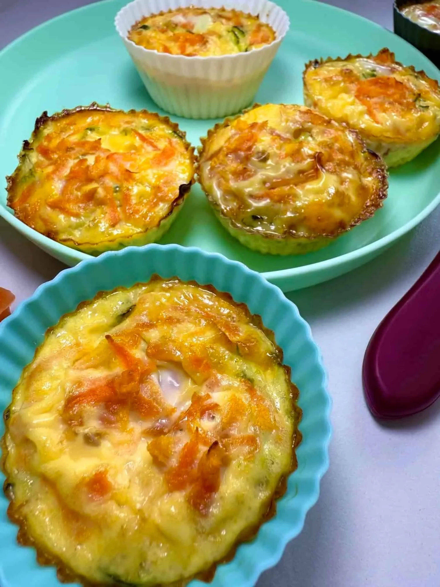 Four baked egg muffins in silicone cases on toddler plate
