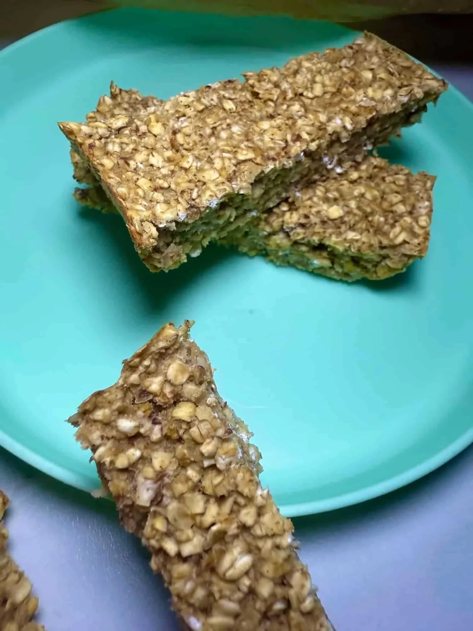 Three baked applesauce oatmeal bars arranged on toddler plate