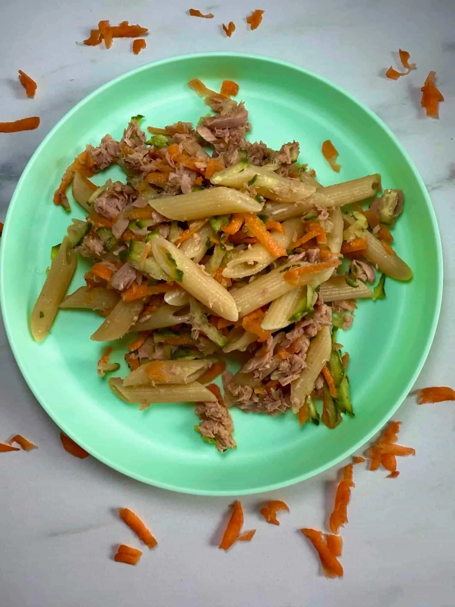 A toddler sized portion of tuna pasta salad with carrot and cucumber