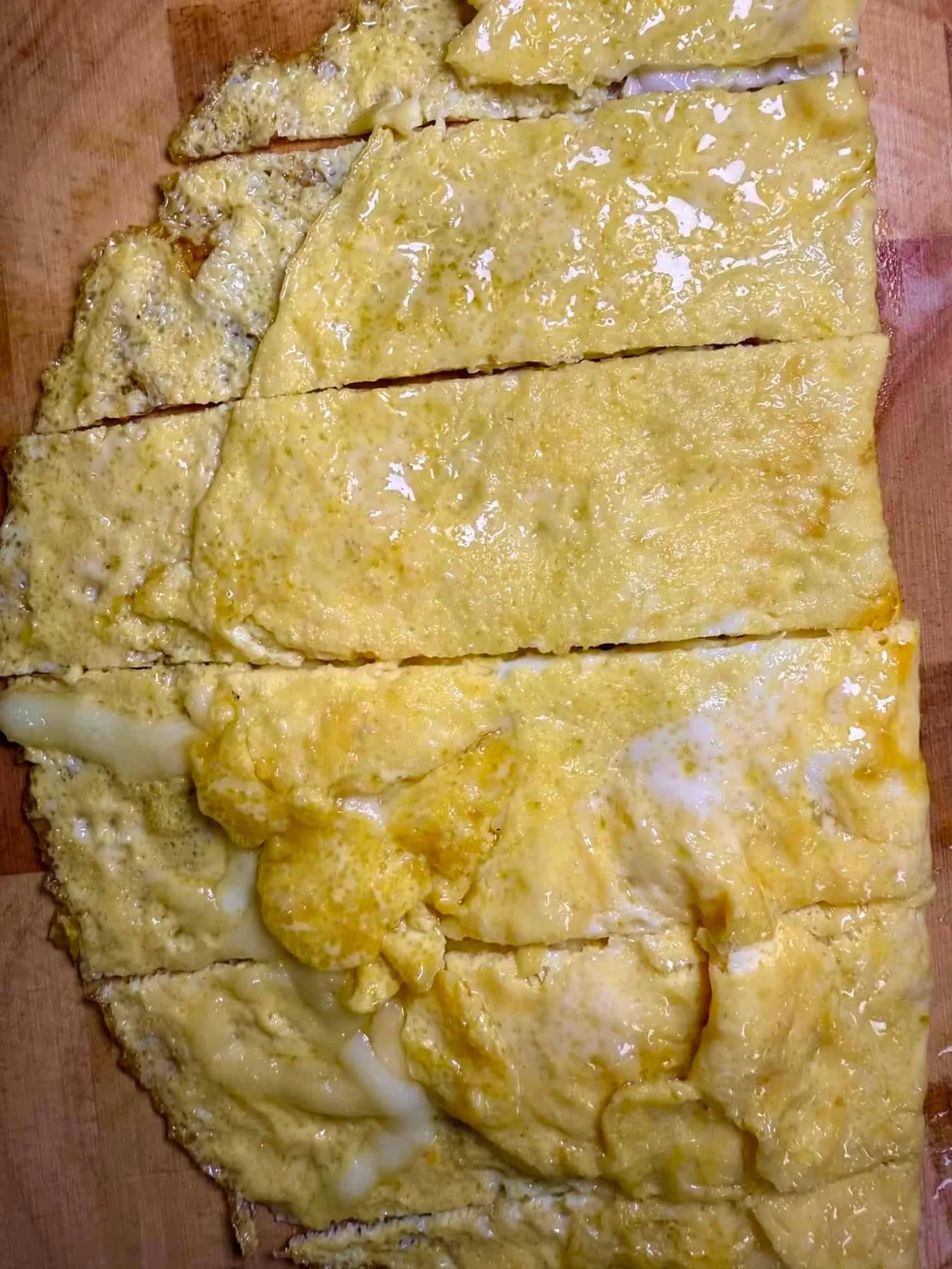 Cooked omelette with cheese, cut into slices and served on wooden board