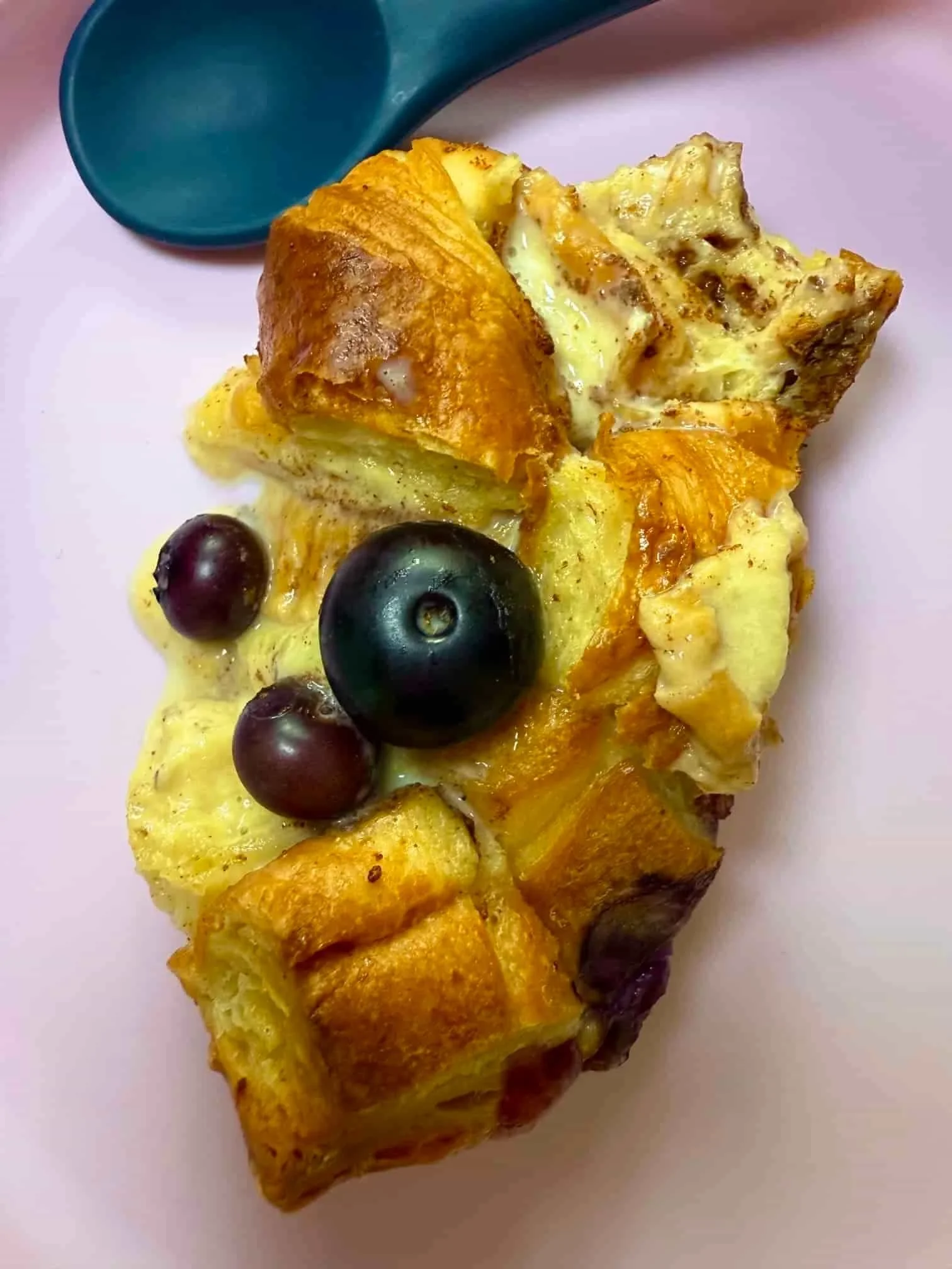 Close up image of a cooked slice of blueberry croissant breakfast bake