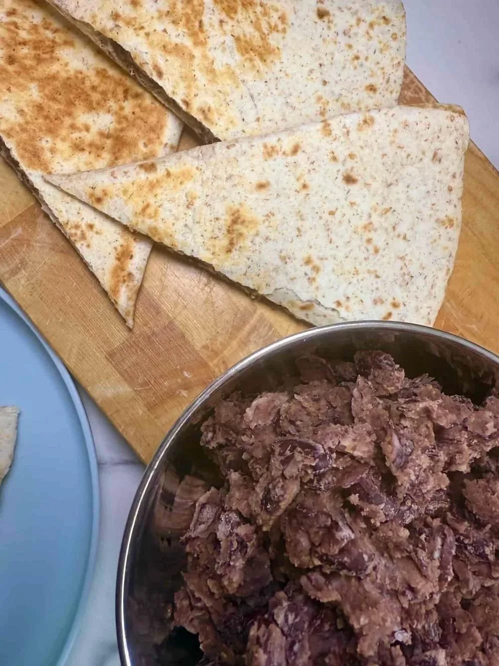 Cooked veggie quesadilla cut into triangles and served on board together with a bowl of the bean filling