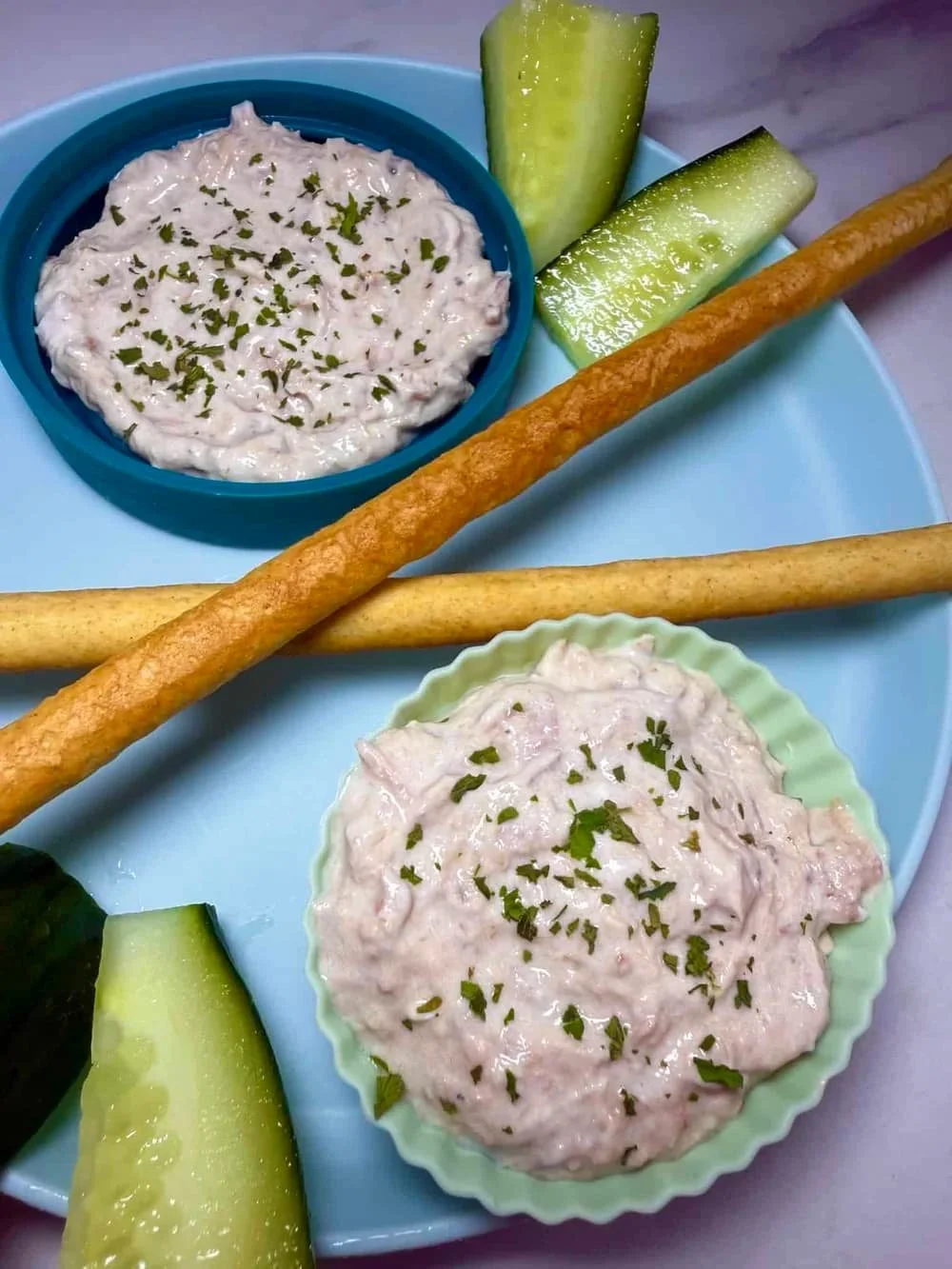 Cream cheese and tuna dip served in silicone case with breadsticks and sticks of cucumber