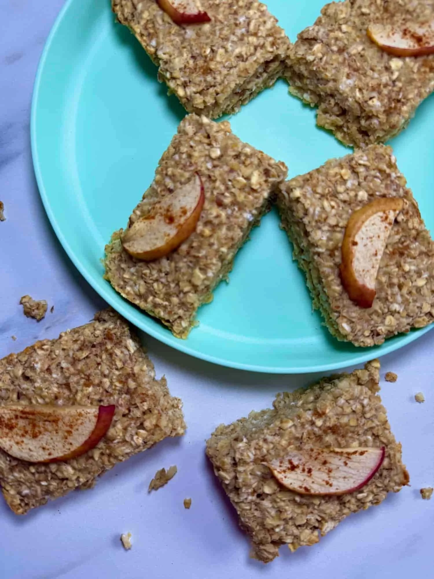 Several apple flapjacks with cinnamon on toddler plate and one on serving board