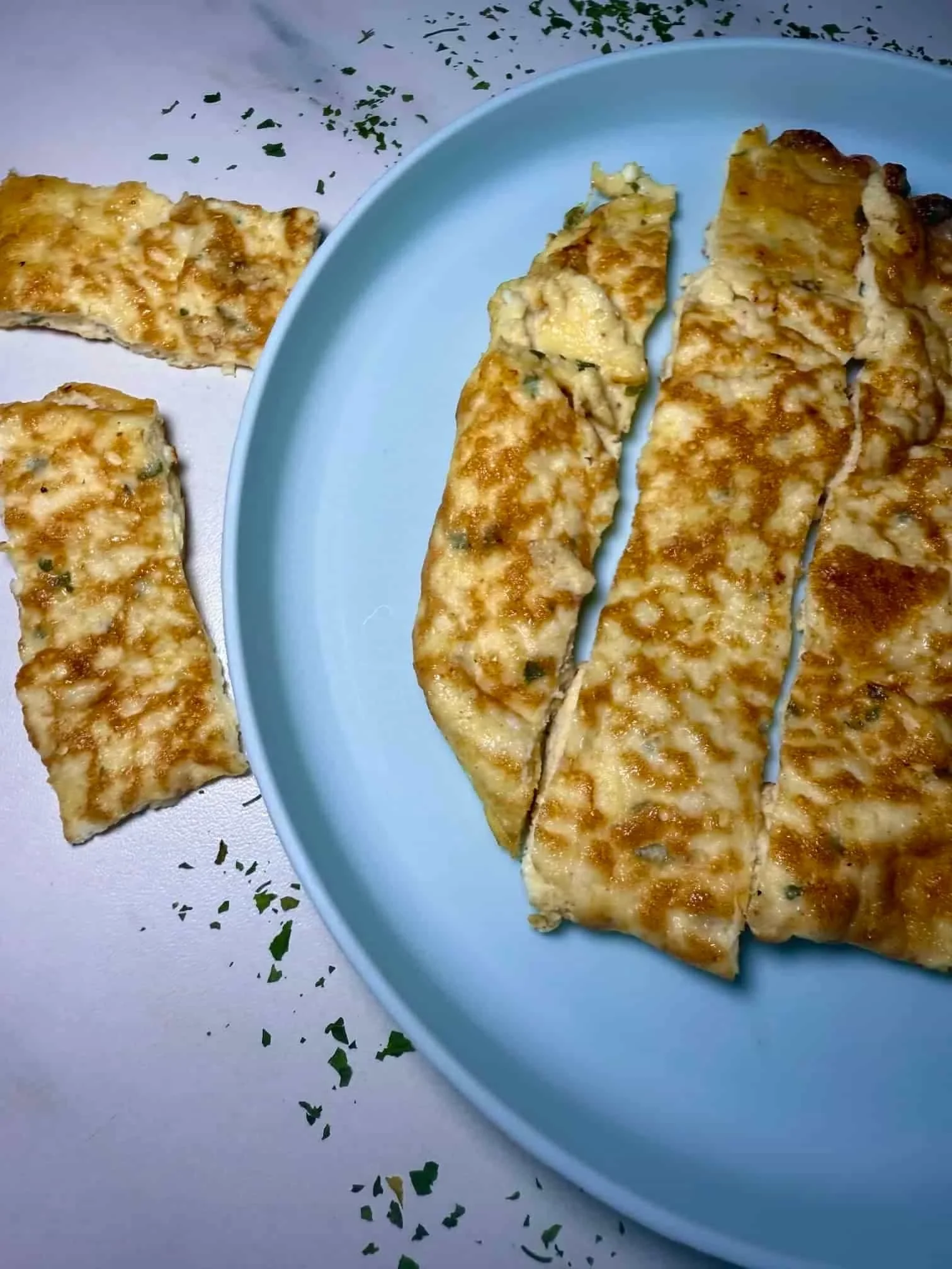 A cooked cottage cheese omlette served on toddler plate and cut into manageable slices