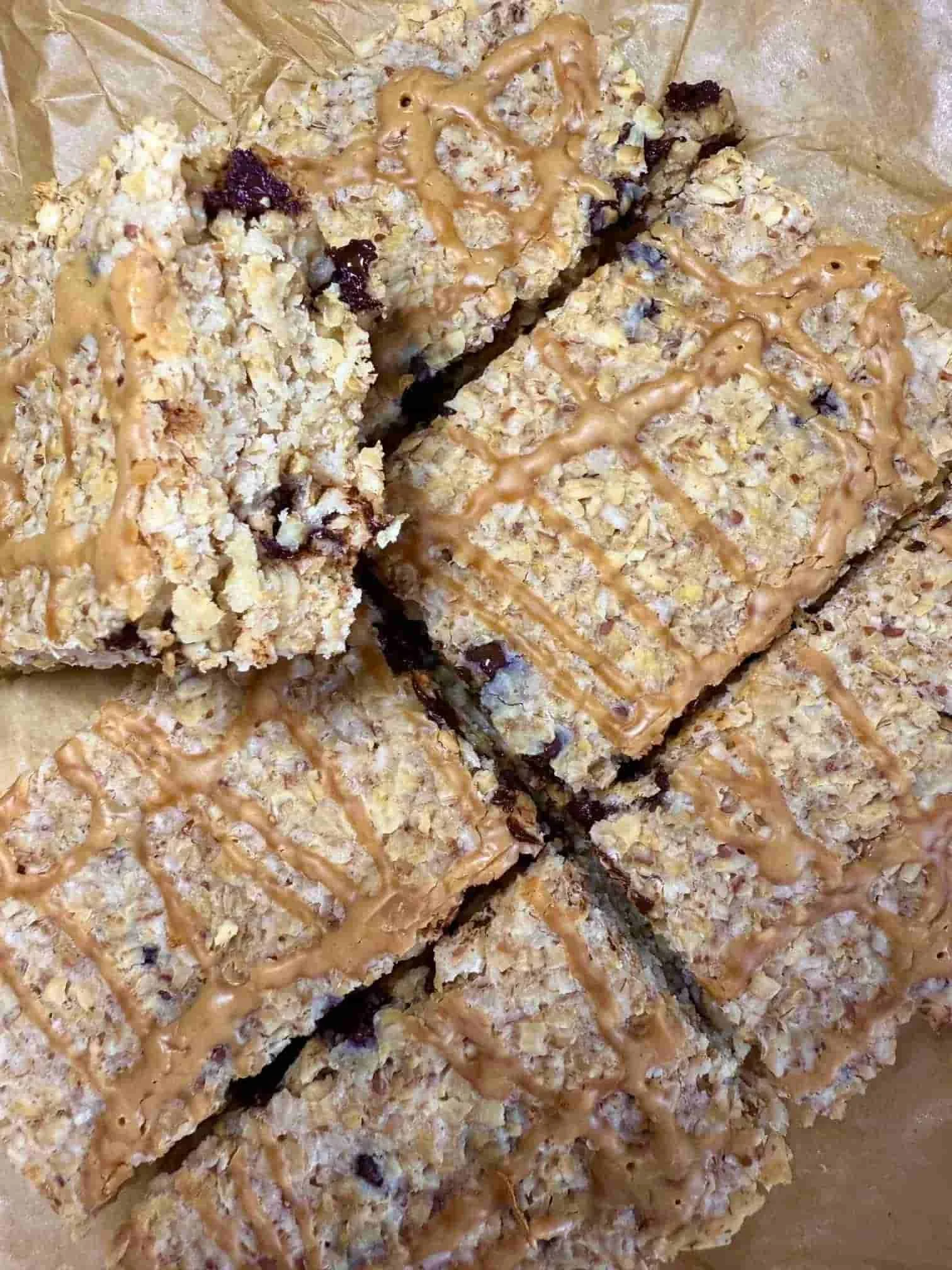 Several baked chocolate chip flapjacks with peanut butter drizzle arranged stacked on a serving board
