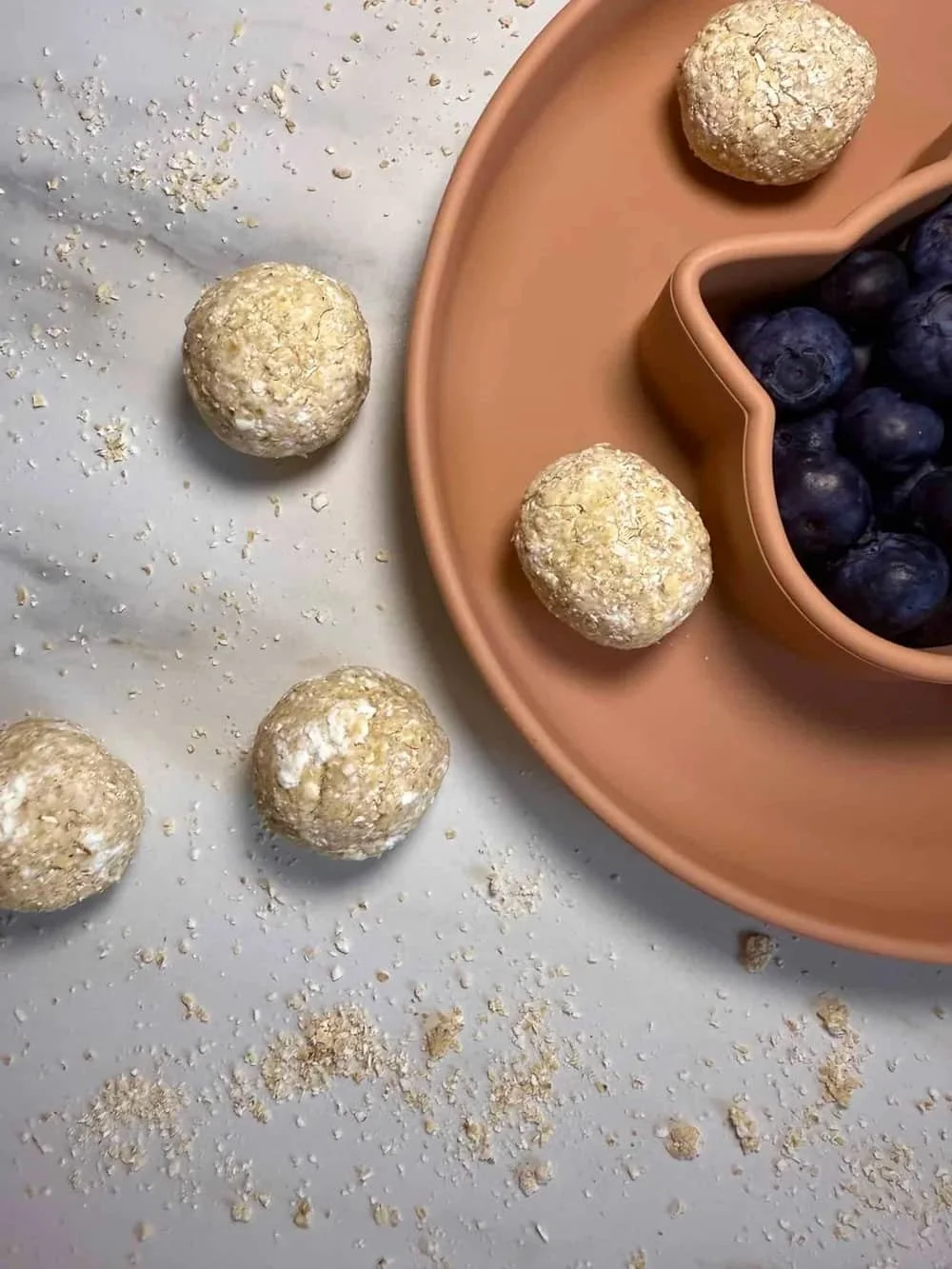 Cottage cheese and oat balls served with blueberries on a toddler plate
