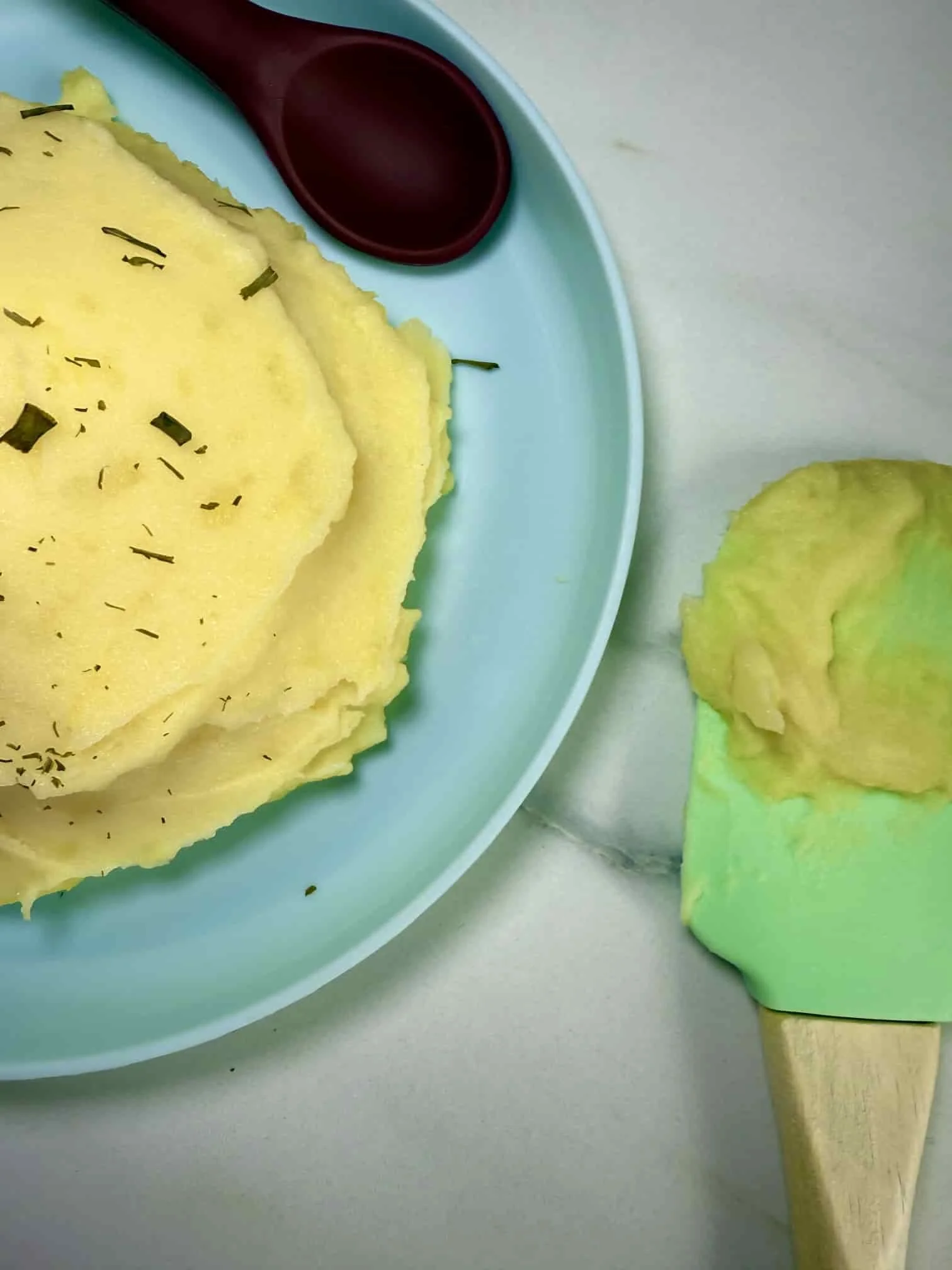 A serving of homemade mashed potato on a toddler plate sprinkled with chives