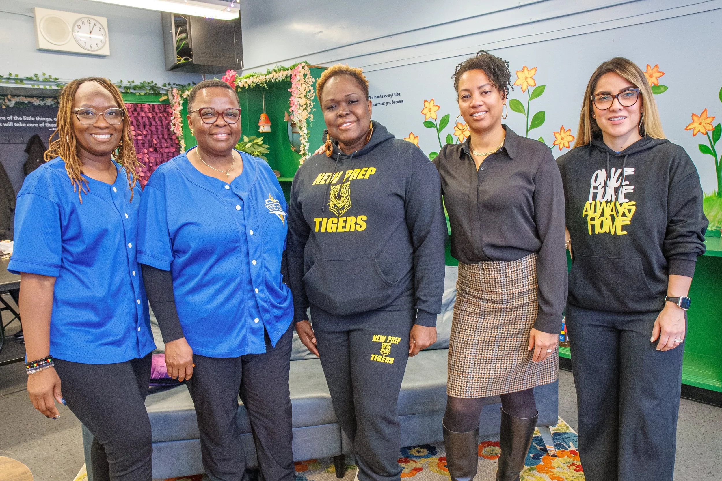 Five school staff members smiling and posing together in a decorated classroom.