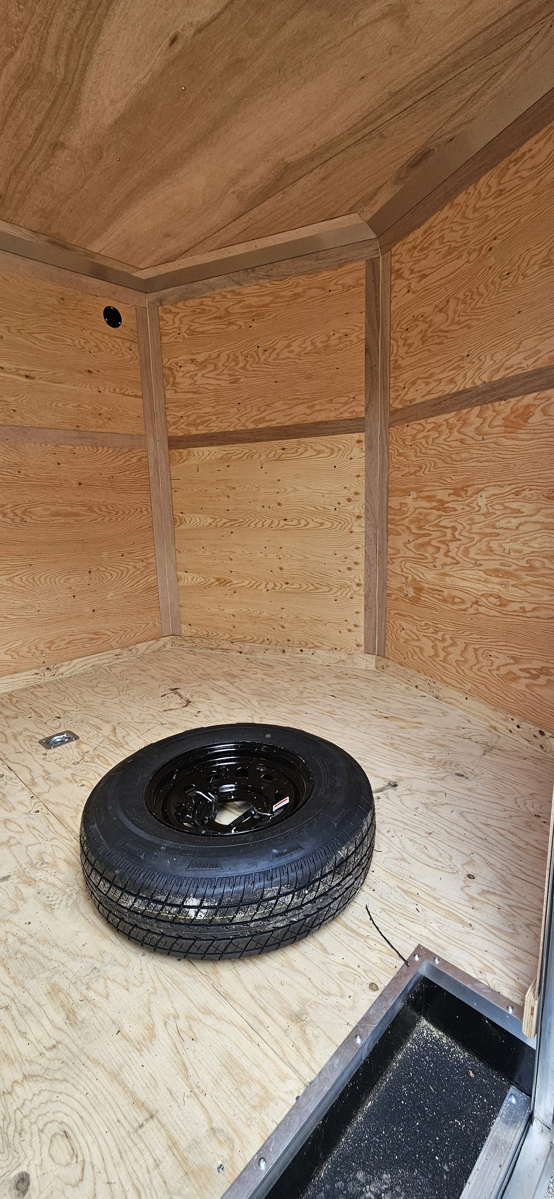 28' Forest River - Continental Cargo - V Series - Enclosed Trailer inside trailer with a spare tire on the floor