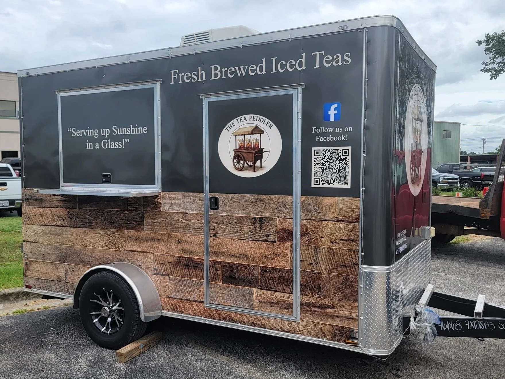 grey concession trailer with a small service window that reads "serving up Sunshine in a glass" above the door it reads Fresh Brewed Iced Teas