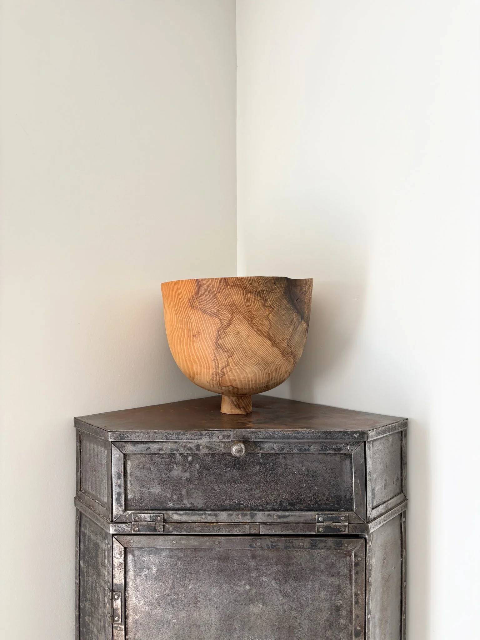 This patinated metal corner unit has a strong utilitarian look, and features one drop down compartment and beneath it a single door cupboard with shelved interior - Bureau Bruton