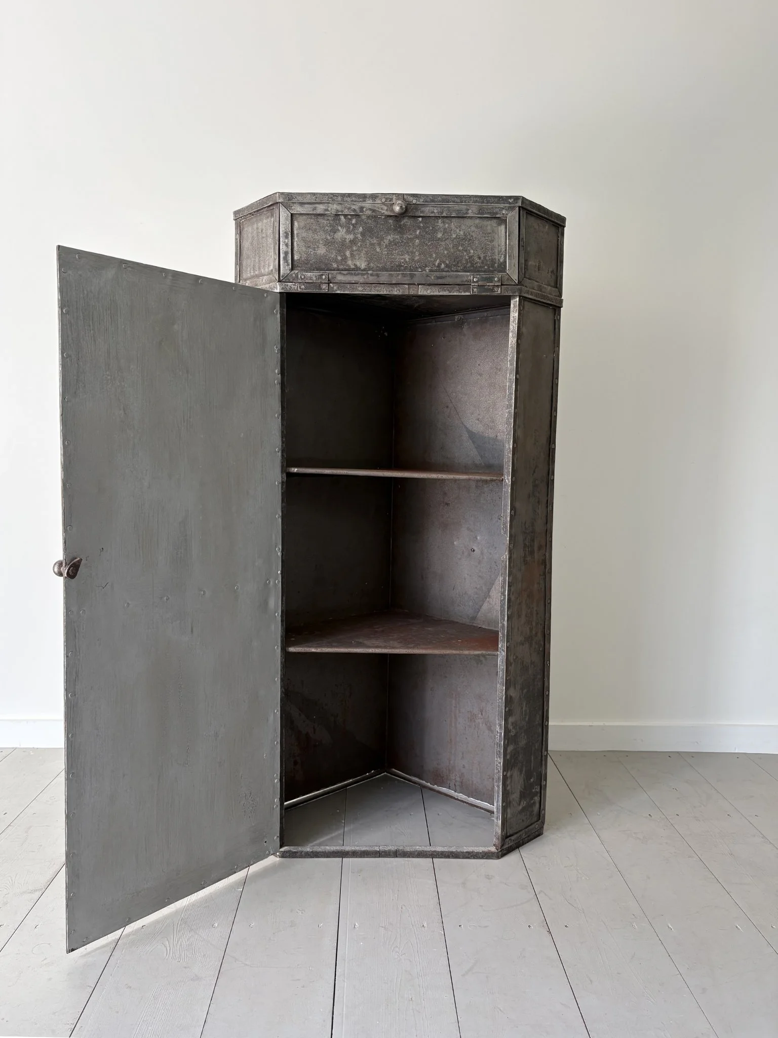 This patinated metal corner unit has a strong utilitarian look, and features one drop down compartment and beneath it a single door cupboard with shelved interior - Bureau Bruton Vintage and Antiques
