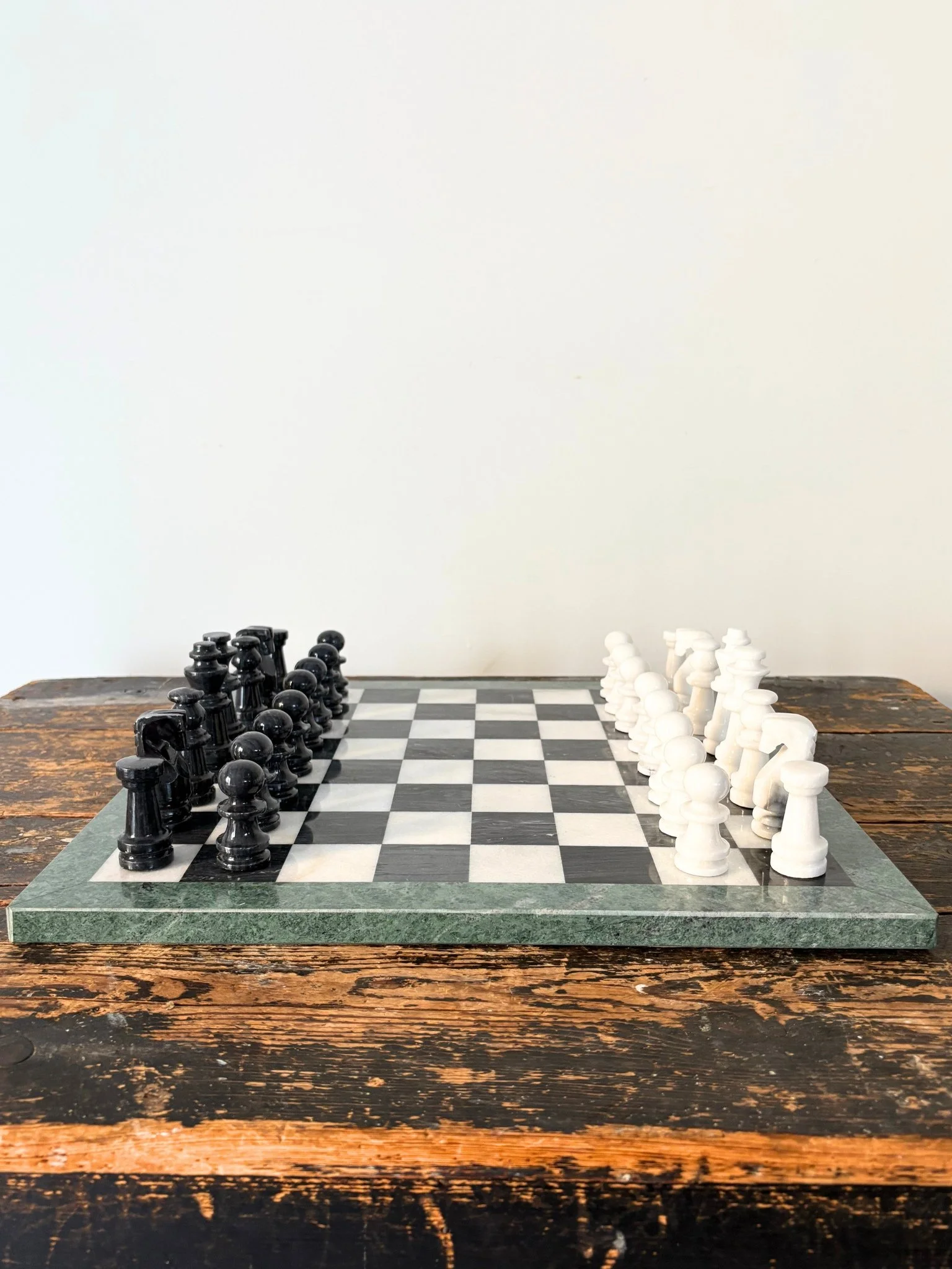 This vintage chess set is handcrafted and has a simple, monochromatic colour palette off set by a green edging to the games board - Bureau Bruton