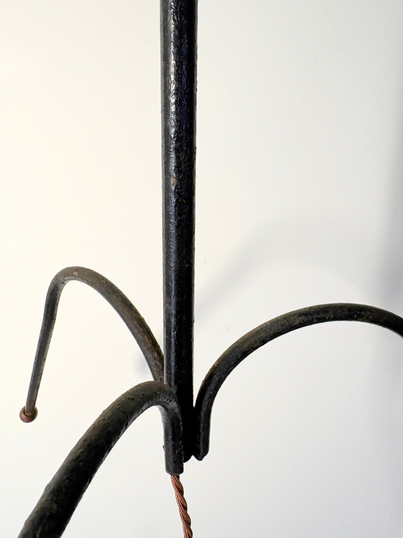 This black metal floor lamp has an arched and splayed tripod base in the manner of Jacques Adnet - Bureau Bruton