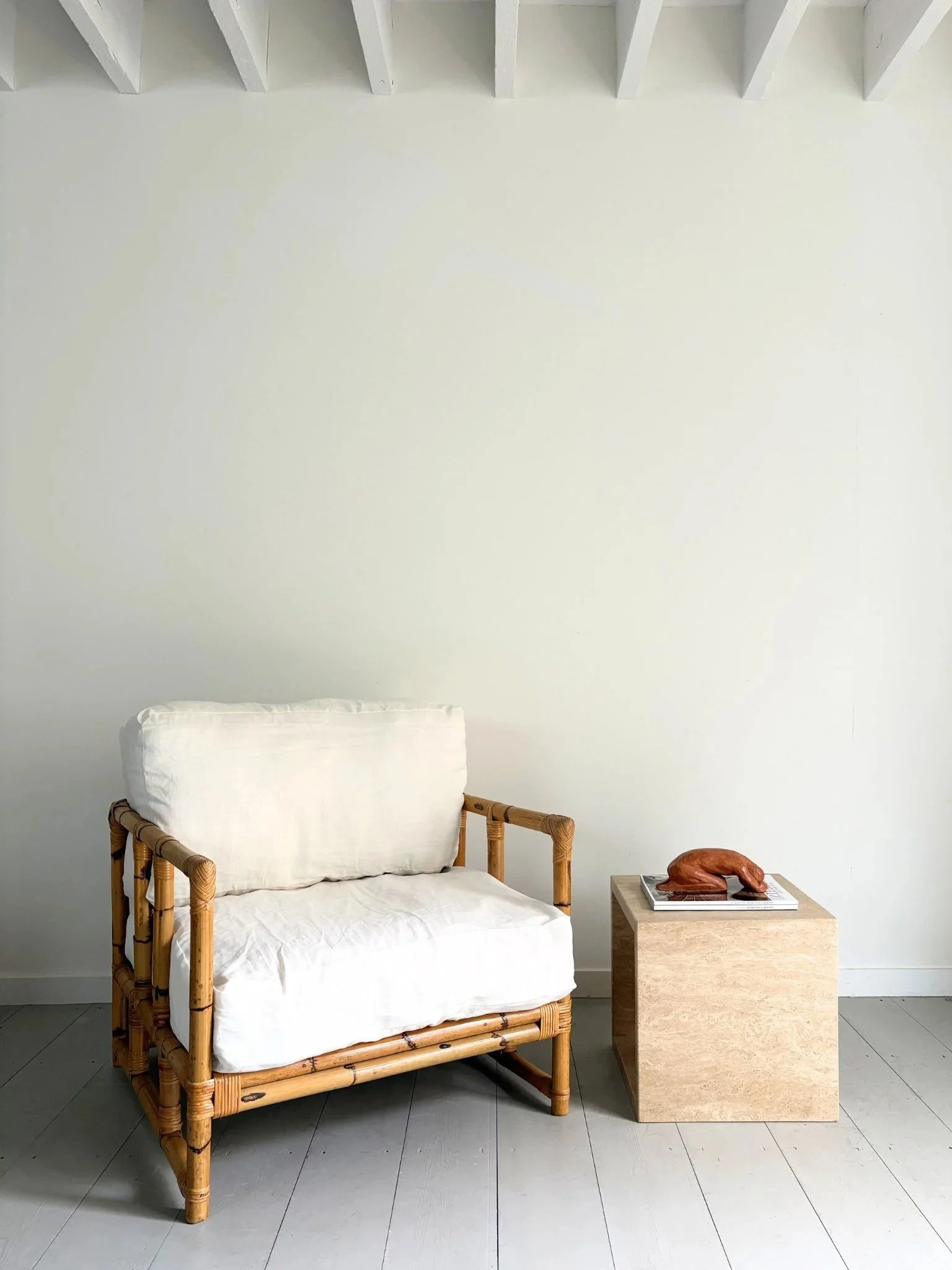An Italian bamboo armchair is paired with a cube side table in travertine marble - Bureau Bruton