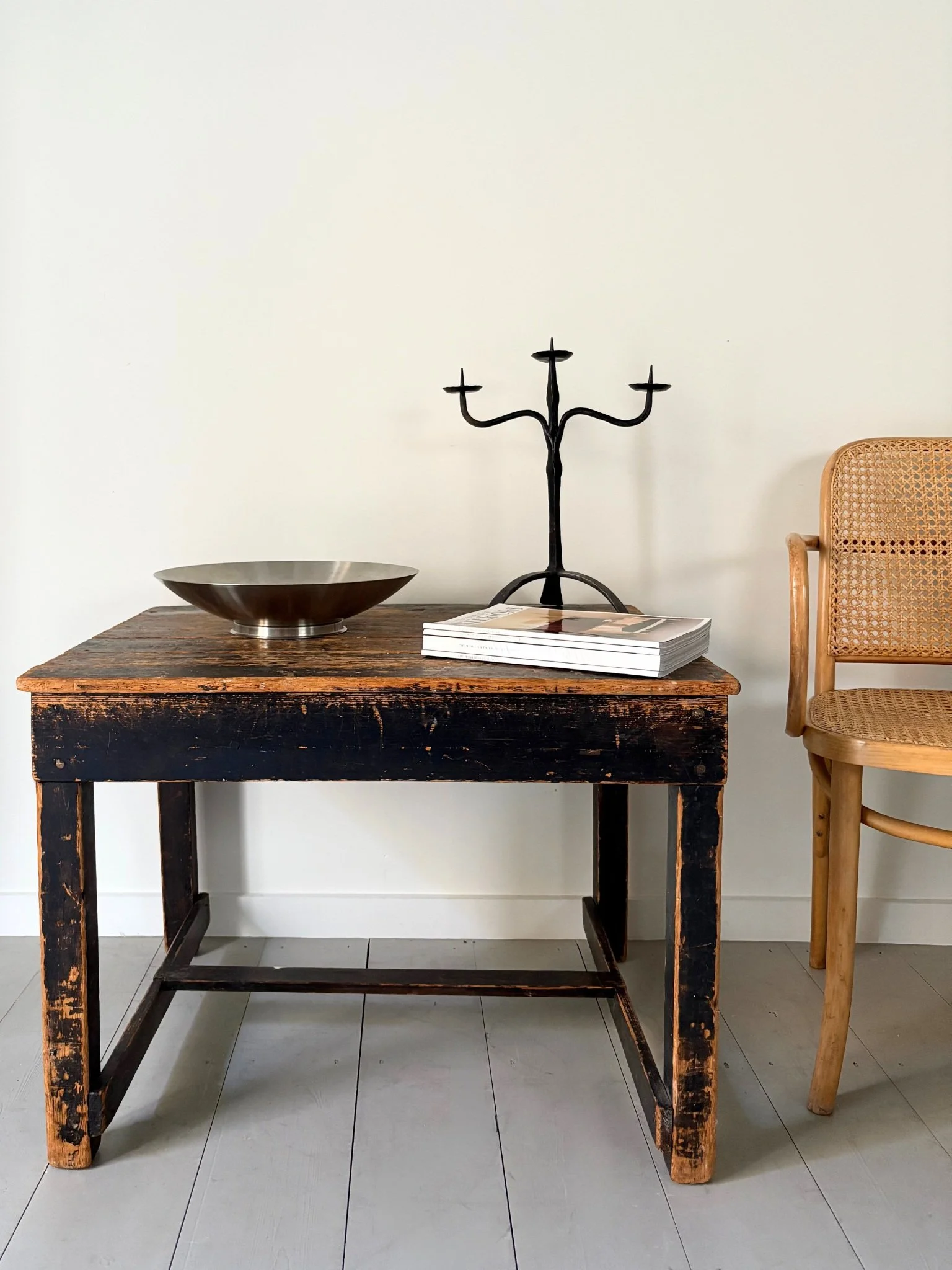 A rustic vintage iron candelabra, styled here with a Potters Table in ebonised pine and a 20th century 811 Thonet chair by Josef Hoffman - Bureau Bruton