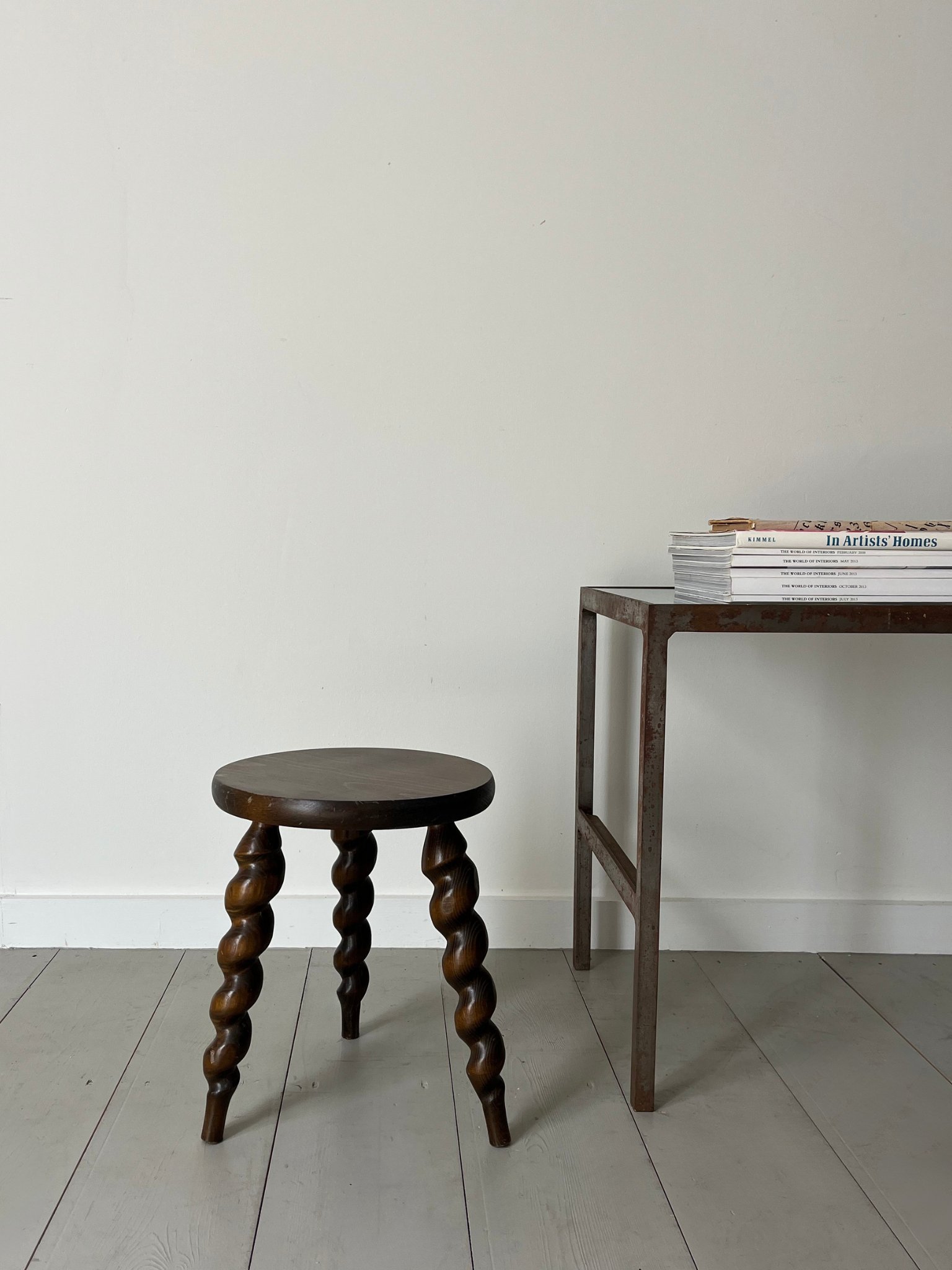 A Patinated Steel Side Table sits next to a French Corkscrew Milking Stool, photographed at the Bureau Bruton showroom