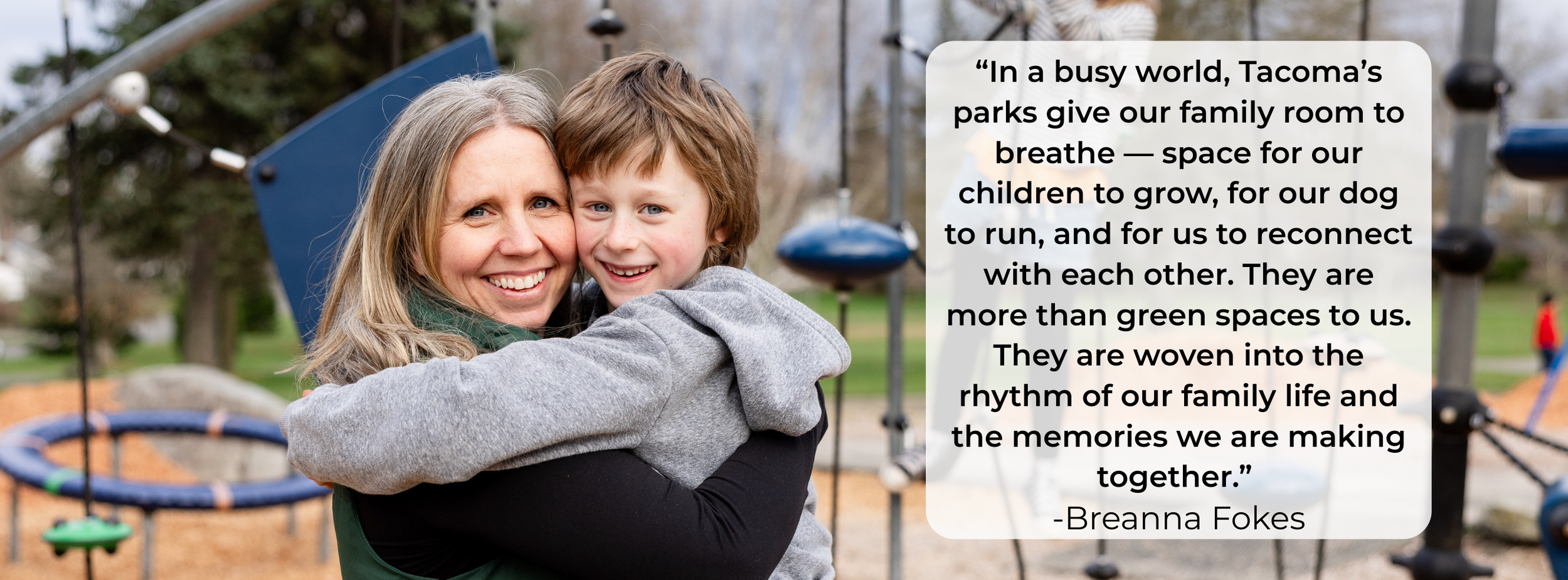 A woman and a young boy hugging and smiling at a park playground.