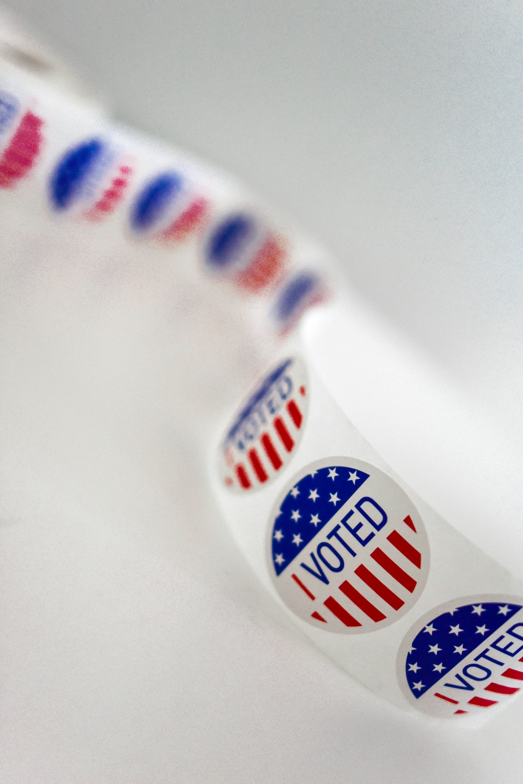 Multiple round patriotic 'I VOTED' stickers with red and blue design on a white background.