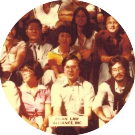 Group of people sitting together at an event, with a sign that reads "Asian Law Alliance, Inc." in front of one person.