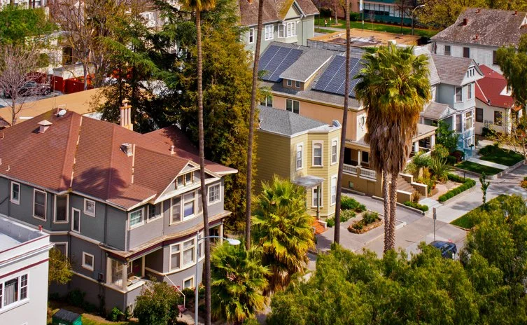 Aerial view of a residential neighborhood with colorful houses, palm trees, and lush greenery.