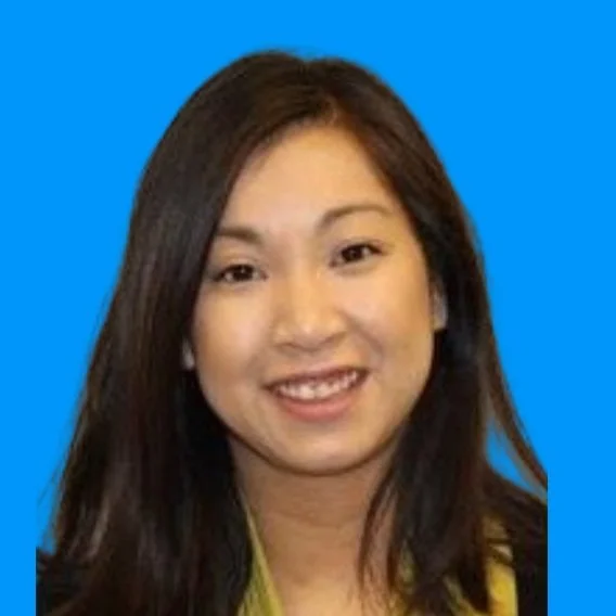 Smiling woman with long dark hair and light skin, wearing a yellow top, against a blue background.
