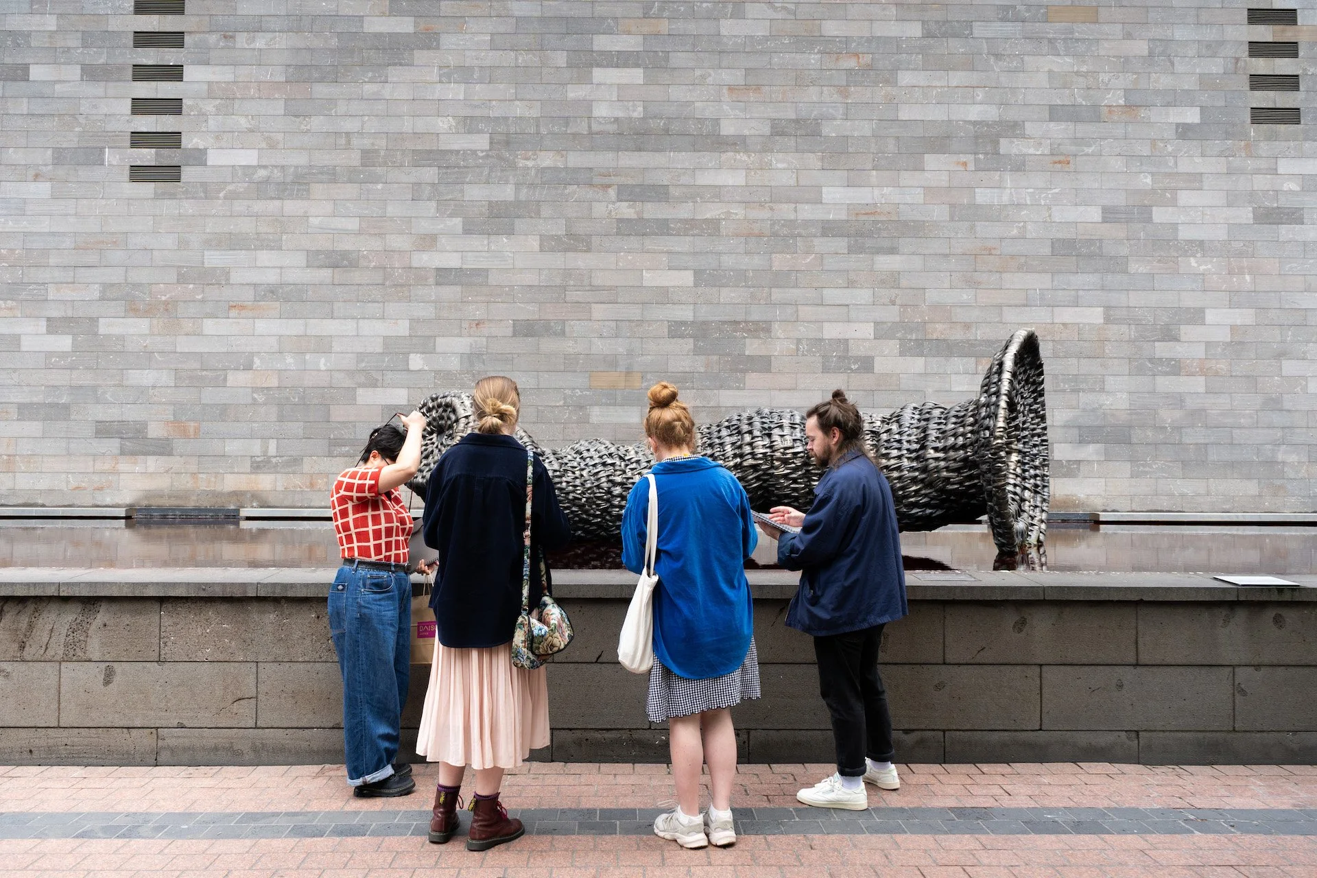 A group of people sketching luk bagurrk gunga (sculpture by Wurundjeri artist Aunty Kim Wandin)