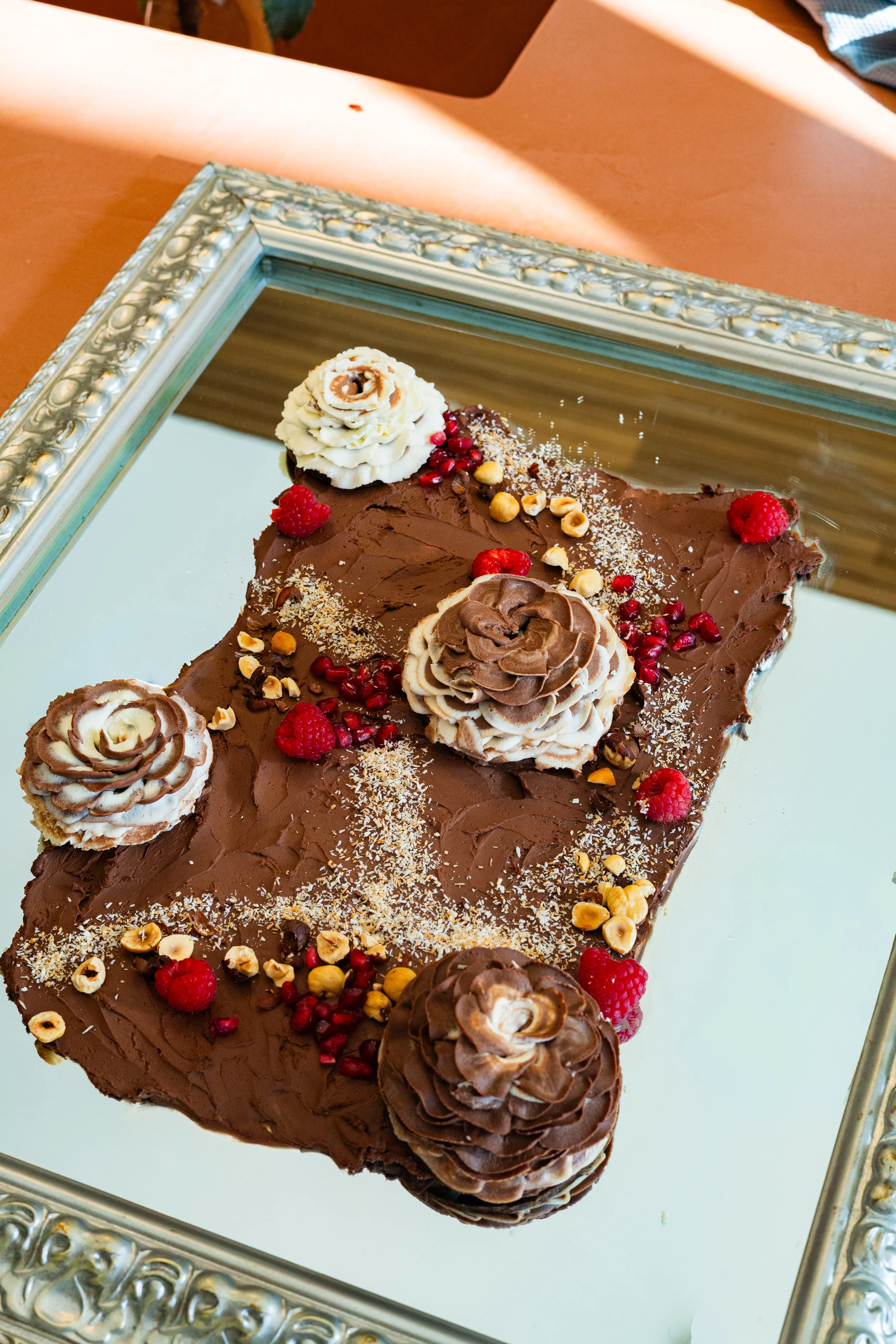 Toile chocolat framboises noisettes sur plateau miroir argenté