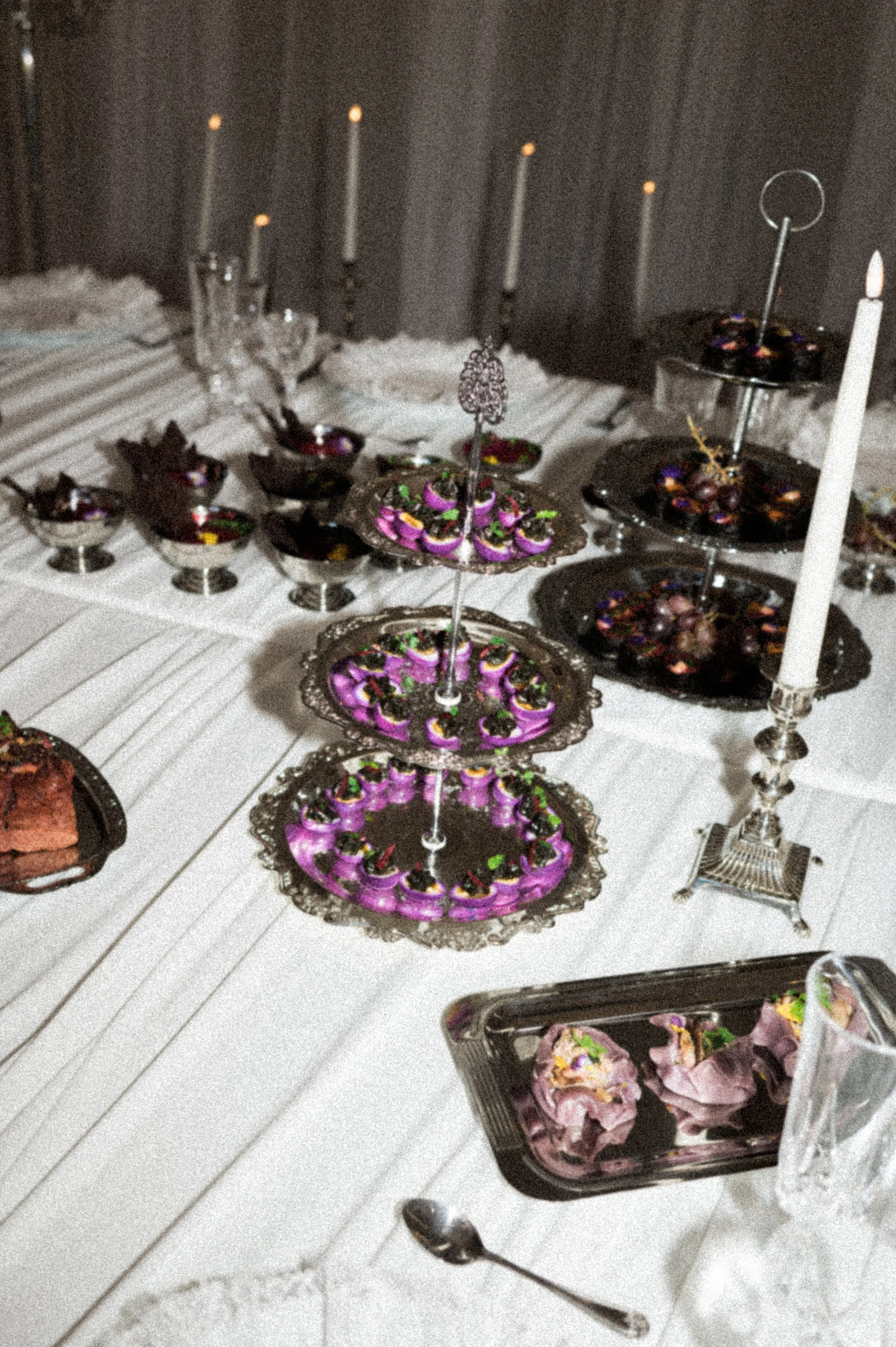 Table de réception avec présentoir argenté à étages garni d'amuse-bouches violets, bougies et verrines, service traiteur prestige à Hossegor, Pays Basque