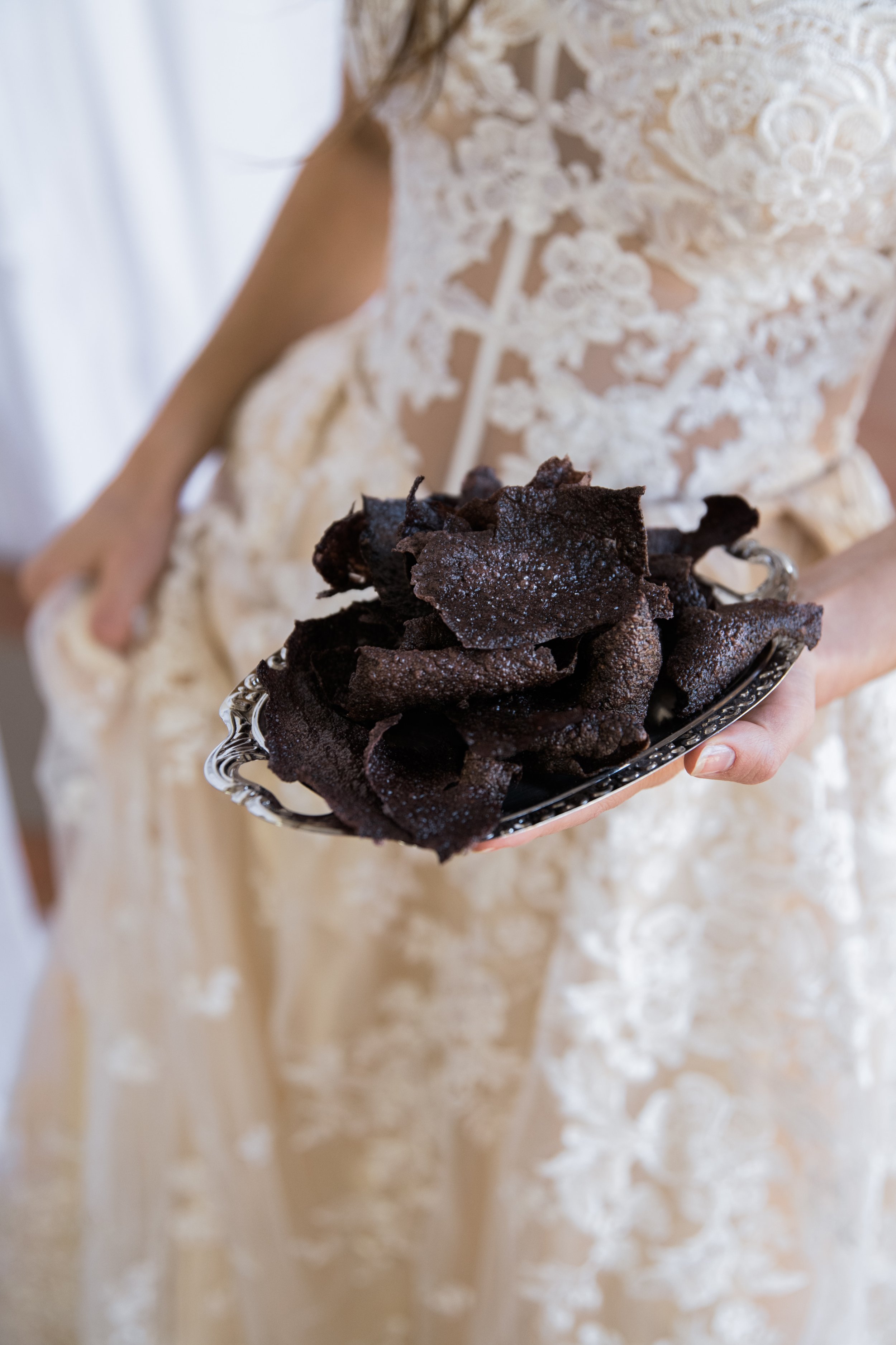 Crackers noirs à la betterave sur plateau argenté tenus par une femme en robe de dentelle, amuse-bouche original du chef traiteur Rémi Blanpoil, Hossegor, Pays Basque, Sud-Ouest