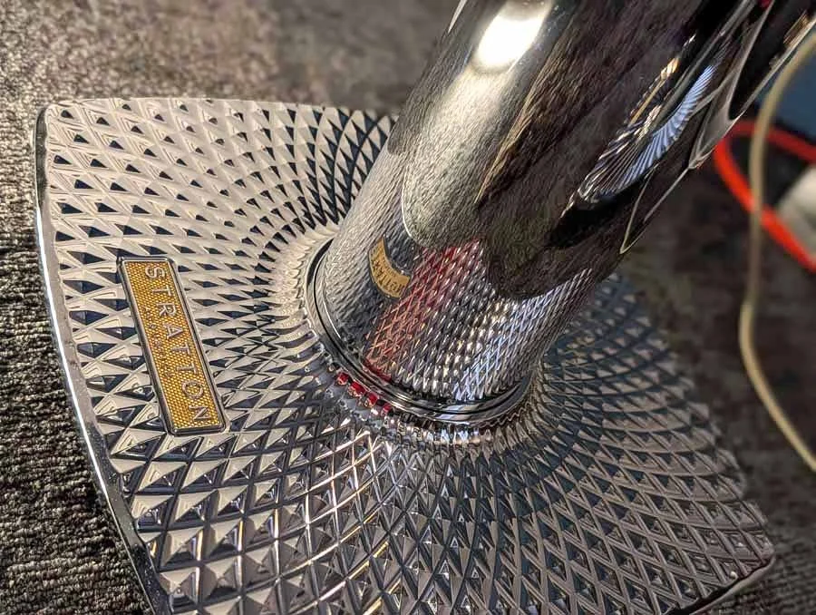 Close-up of a shiny, textured metal base of Stratton Acoustics Element 8 loudspeaker stands, Chrome plated cylindrical leg on textured base.