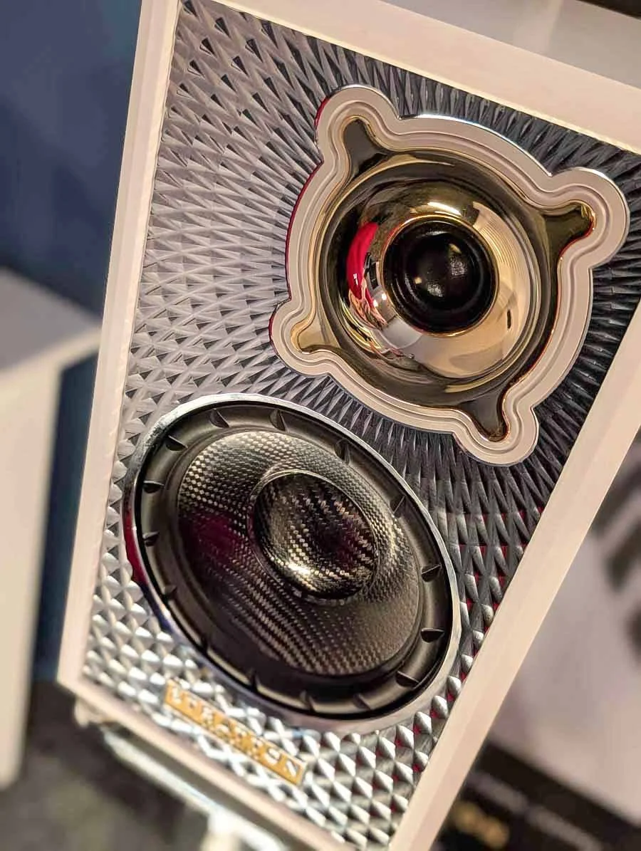 Close-up of the Stratton Acoustics Element 8 high-end speaker with a chrome facia and white casing, showing two large black speaker drivers and a shiny gold horn.